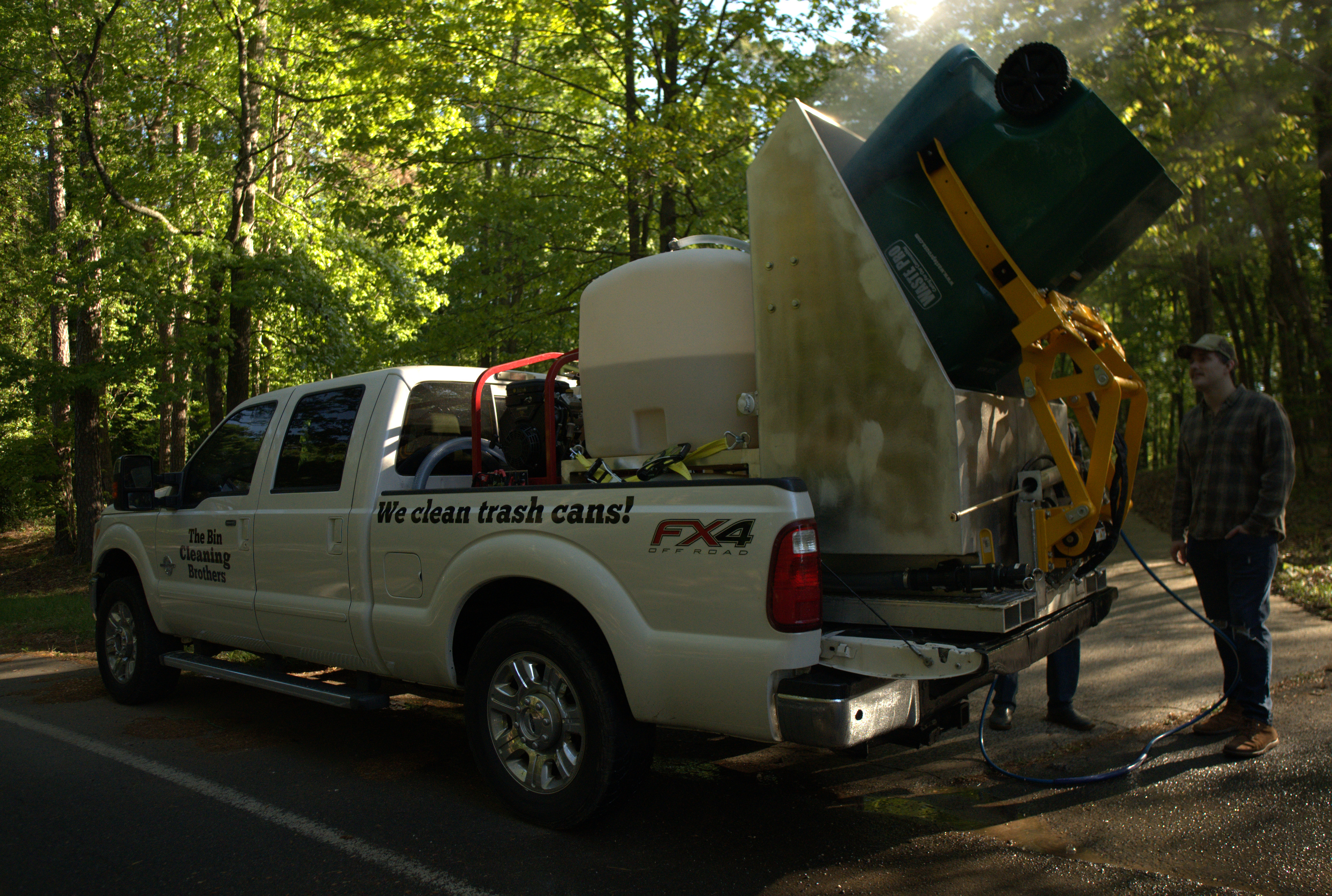 The Bin Cleaning Brothers truck and crew cleaning trash bins at golden hour in North Georgia