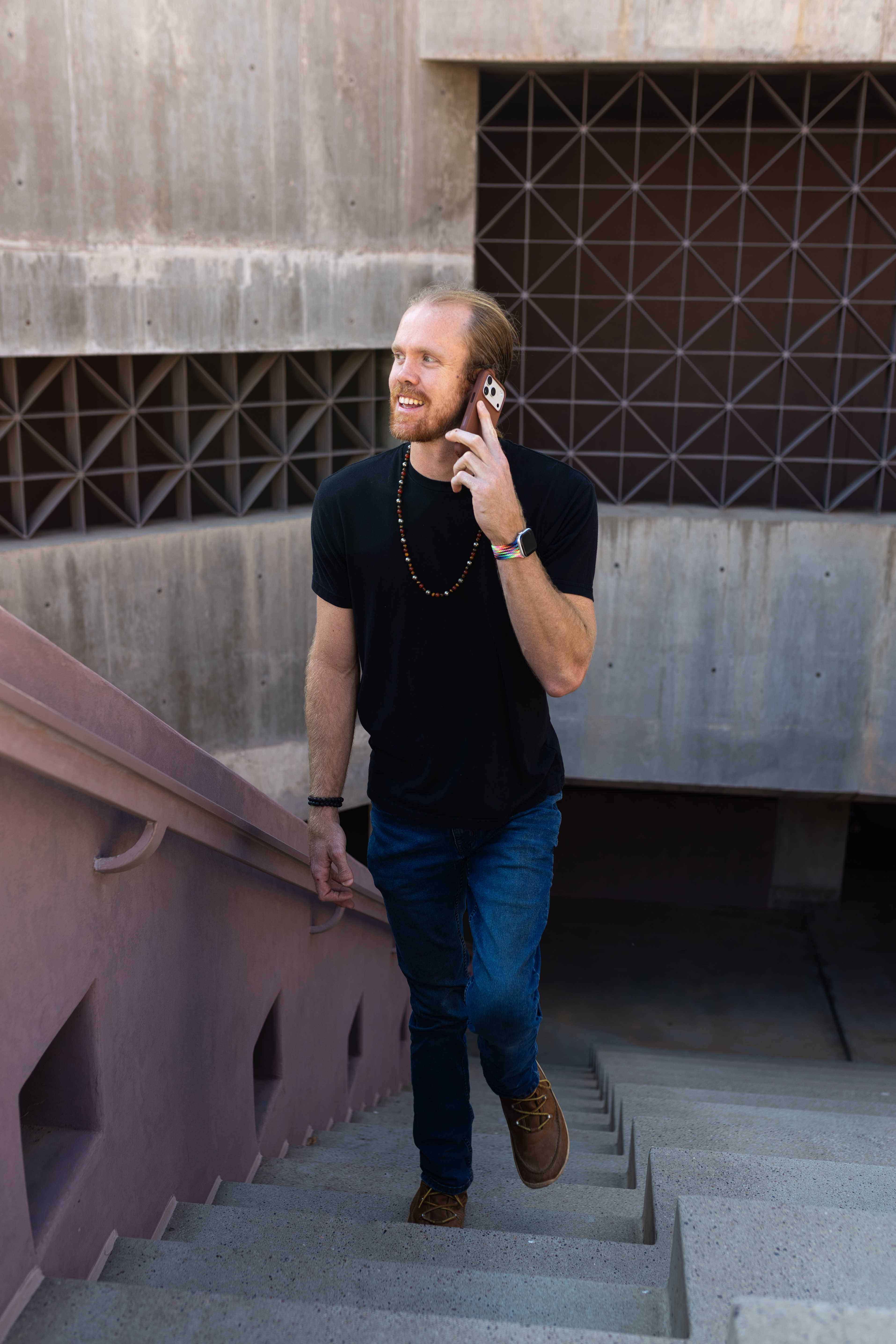 Cody Fitzgerald walking up stairs while on a phone call, urban Phoenix architecture in the background