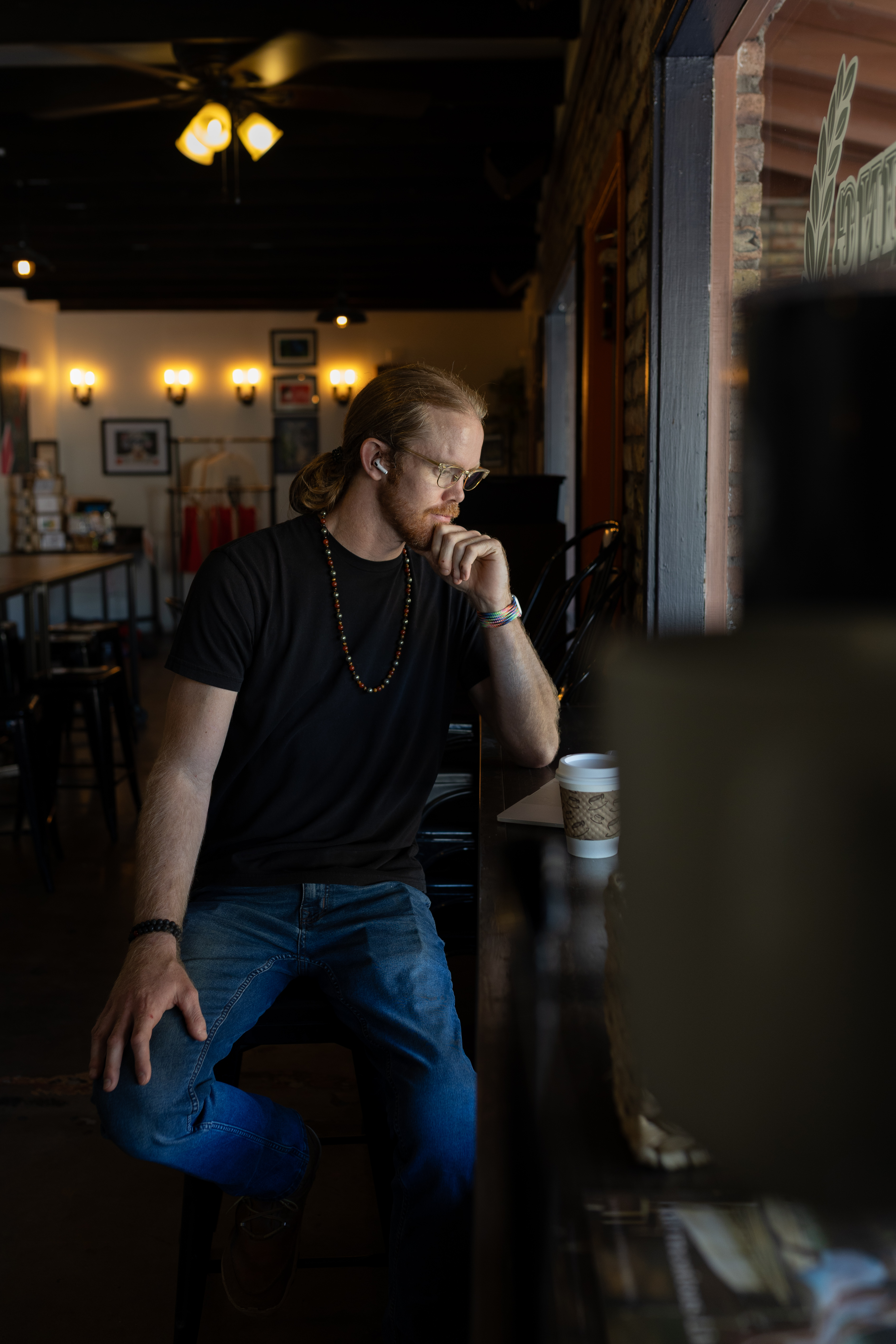 Cody Fitzgerald working from a Phoenix coffee shop, glasses on, thoughtful
