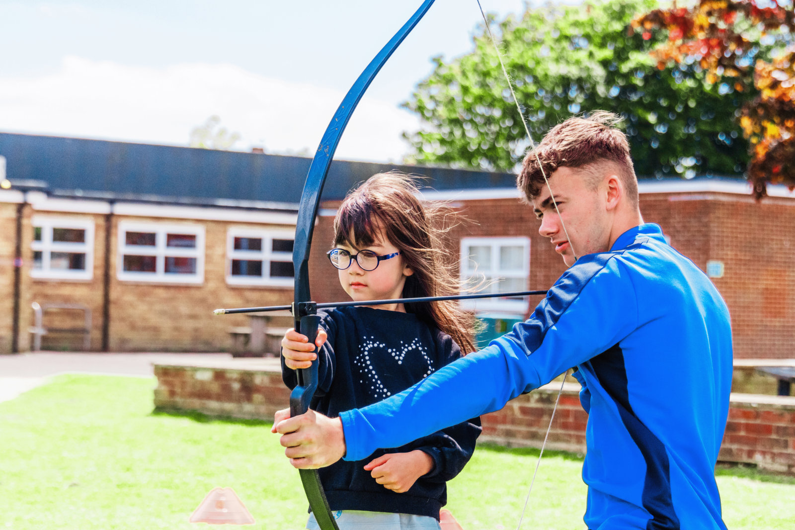JC Sports coach teaching a girl archery