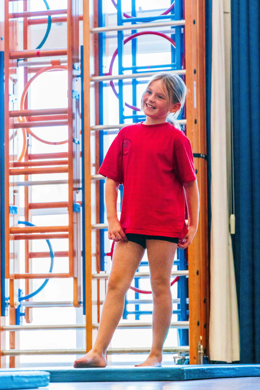 Girl on climbing apparatus in a school hall