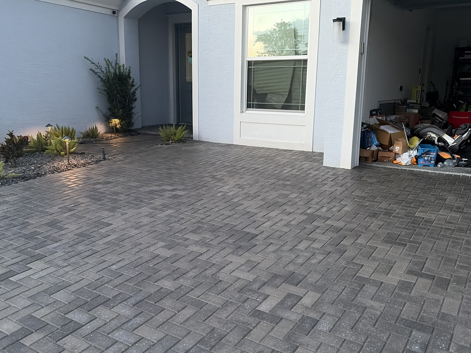 Clean paver driveway and home entrance at twilight with landscape lighting