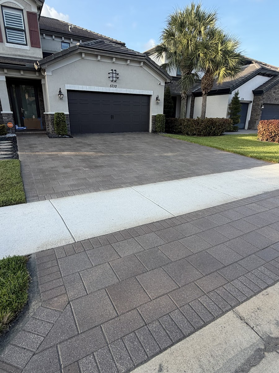 Clean multi-toned paver driveway leading to a grey stucco home