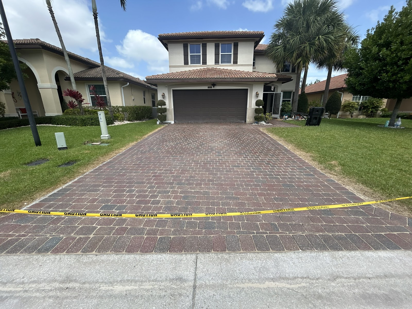 Newly cleaned and sealed paver driveway marked with caution tape