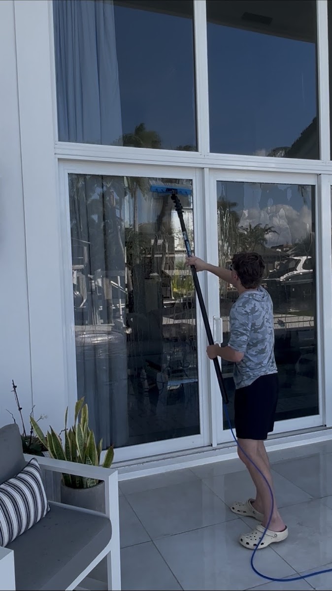Worker cleaning sliding glass doors with a squeegee extension pole