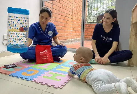 Eli Bohórquez en una sesión de estimulación temprana con un bebé y su mamá