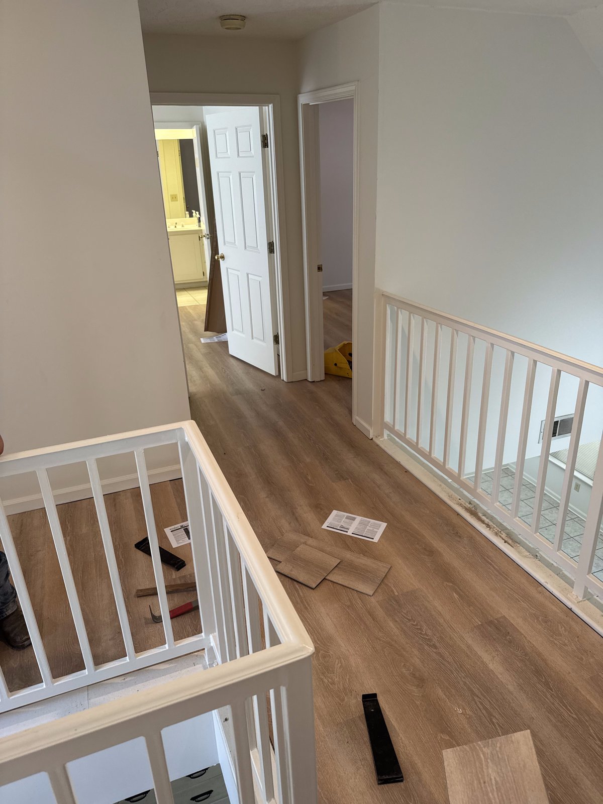 Upstairs hallway with new plank flooring and white railings by Boren Construction