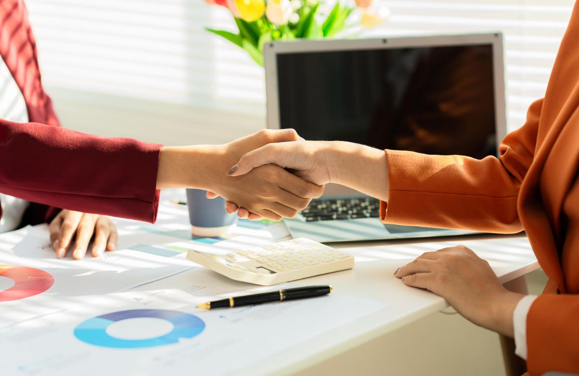 Two people reviewing documents at a desk related to selling a home