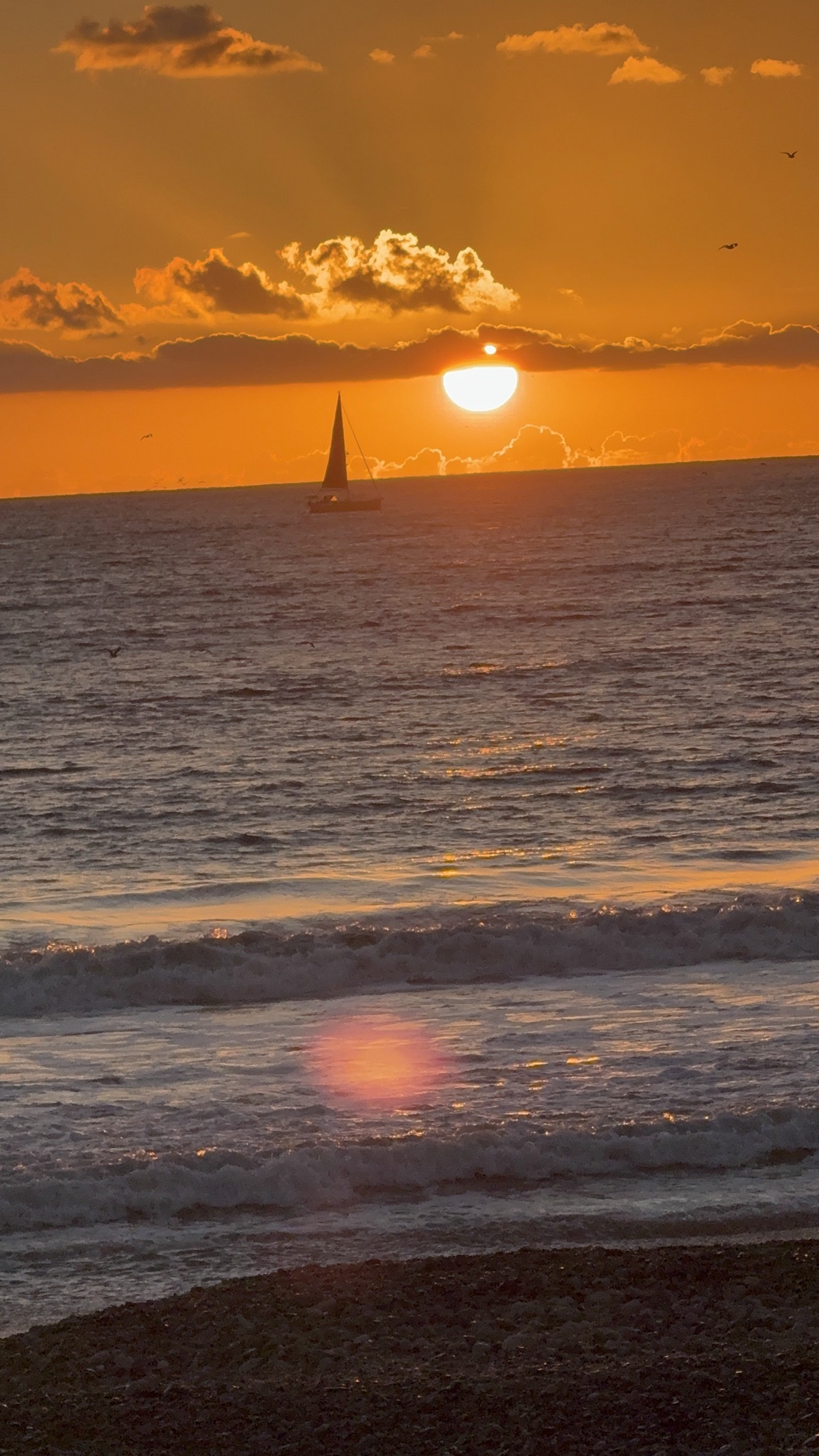 Sunset over the water with a sailboat off the Orange County coast