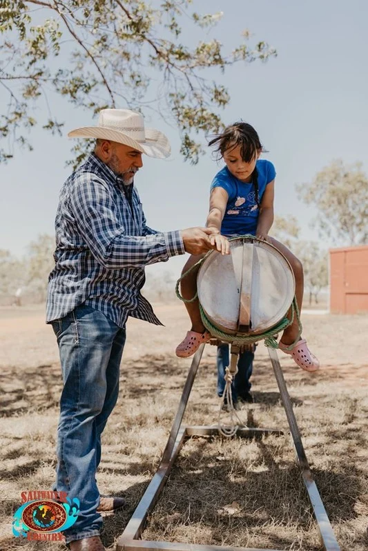 Instructor helping girl on practice barrel