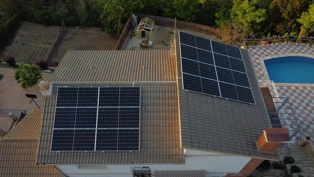 Casa con piscina y placas solares en dos faldones del tejado, vista desde un dron