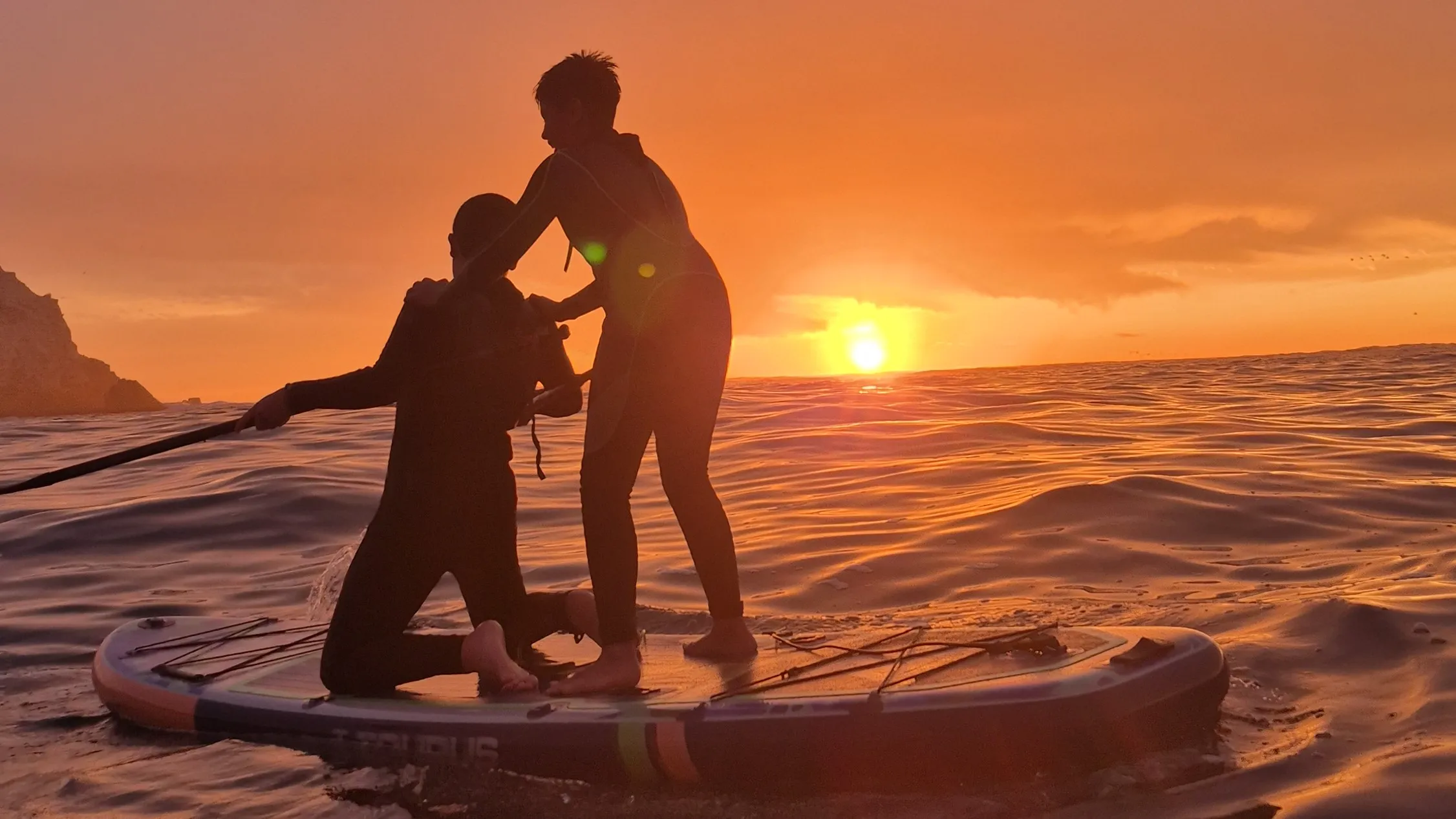 Persona remando en SUP al atardecer