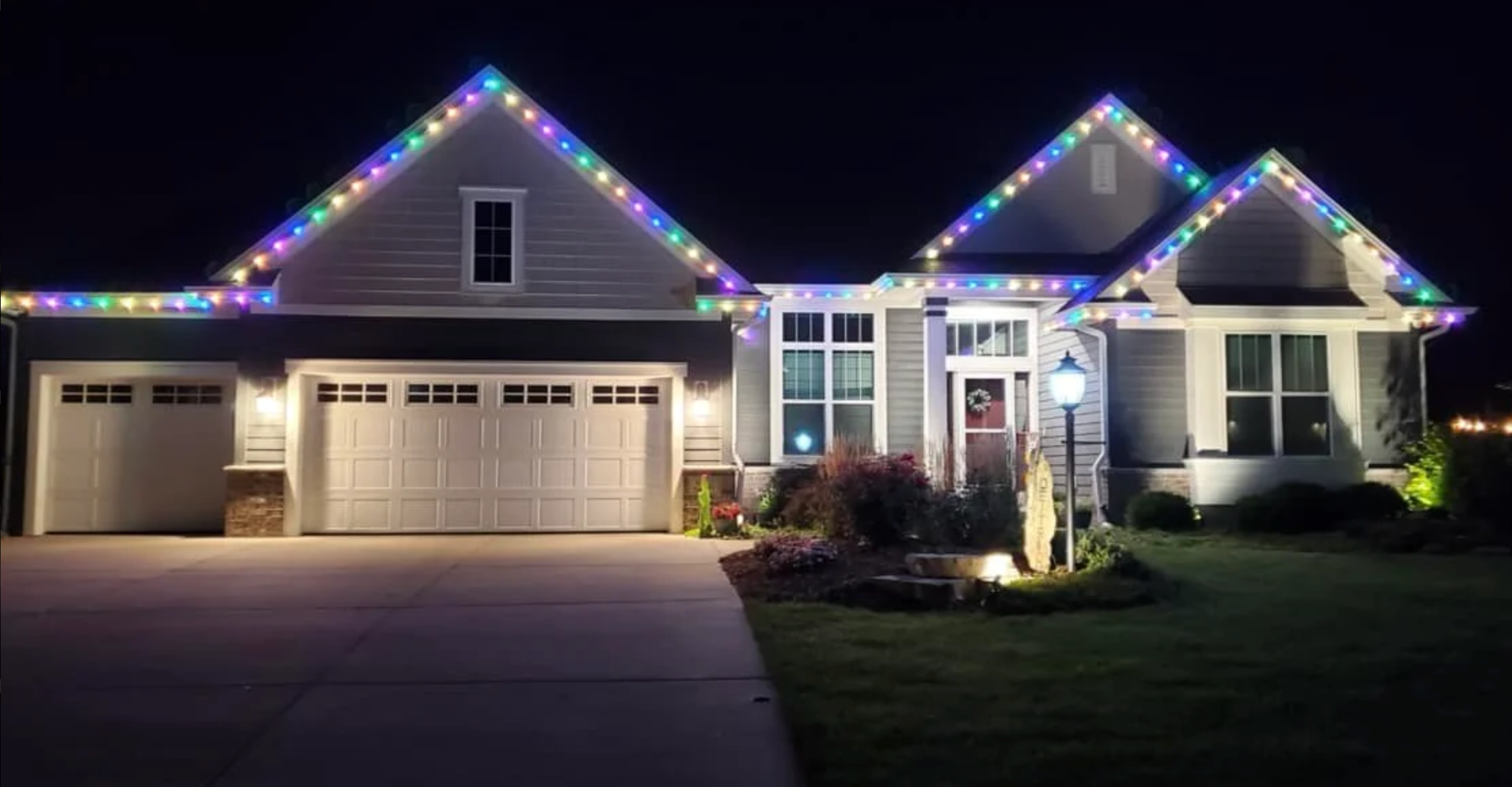 Christmas light display with illuminated roofline and wrapped shrubs