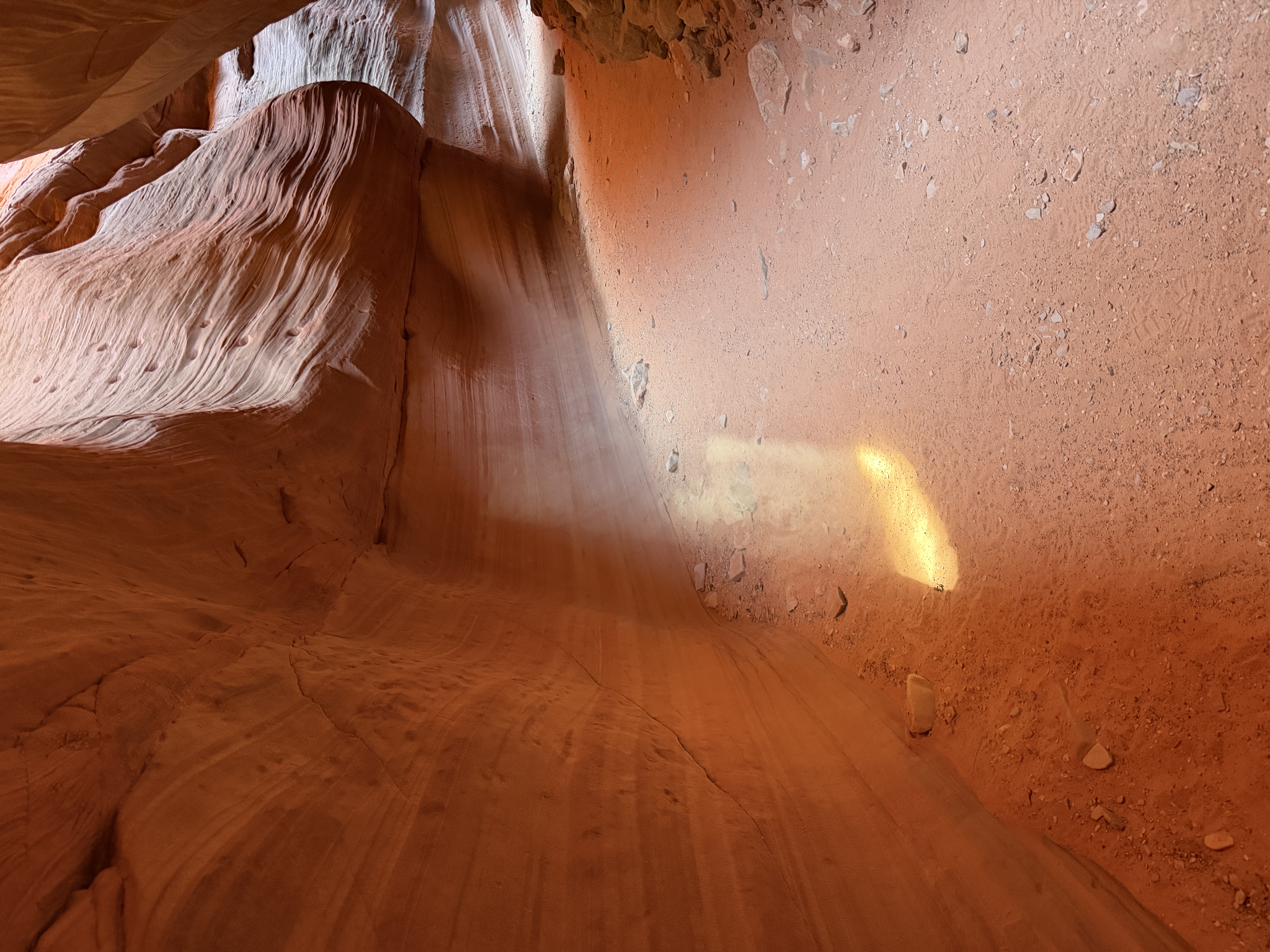 Light beam illuminating the sandy ground inside a smooth red sandstone slot canyon. Light beam illuminating the sandy ground inside a smooth red sandstone slot canyon.