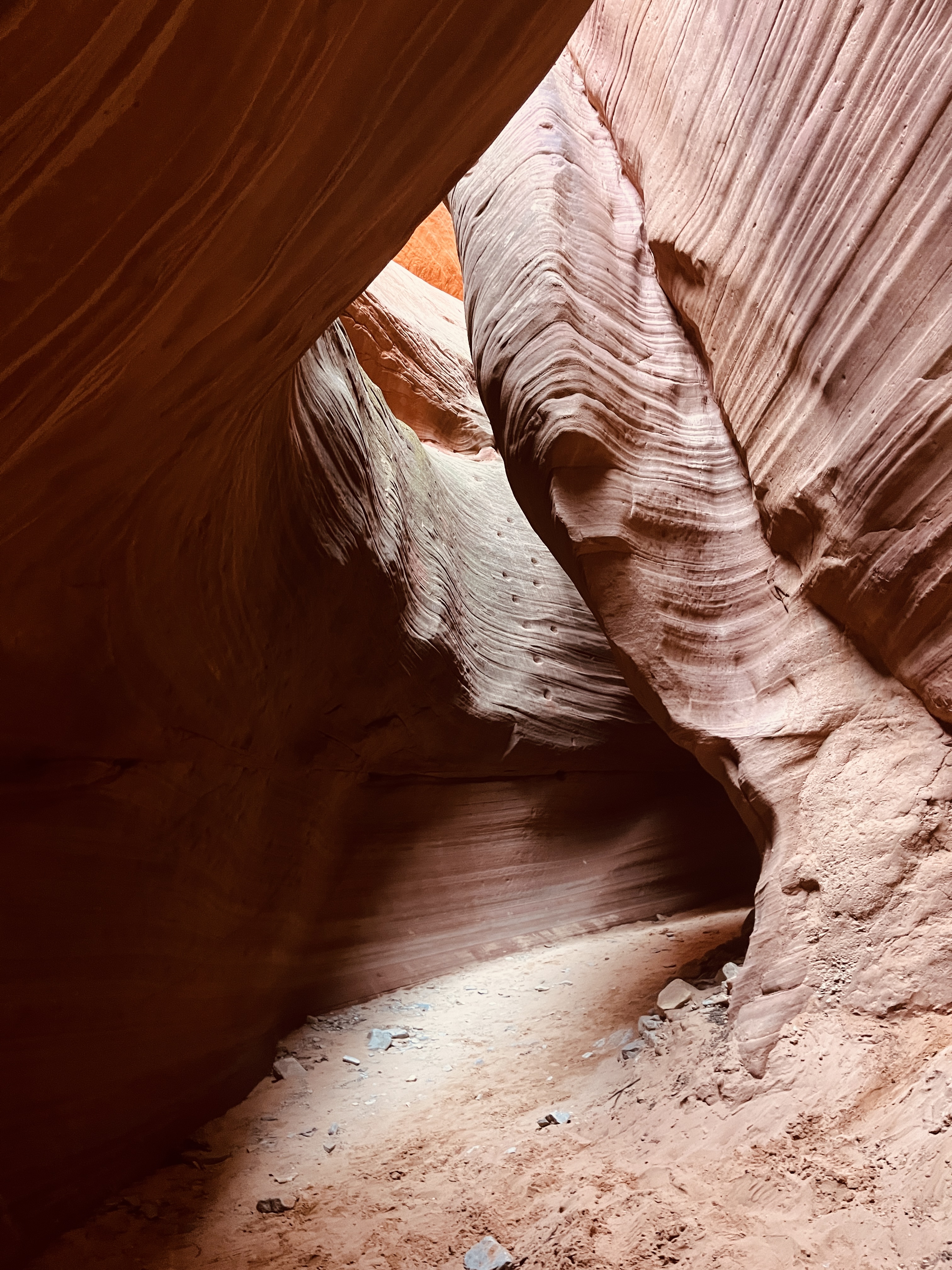 Smooth, layered sandstone walls framing a dimly lit passage in a slot canyon. Smooth, layered sandstone walls framing a dimly lit passage in a slot canyon.