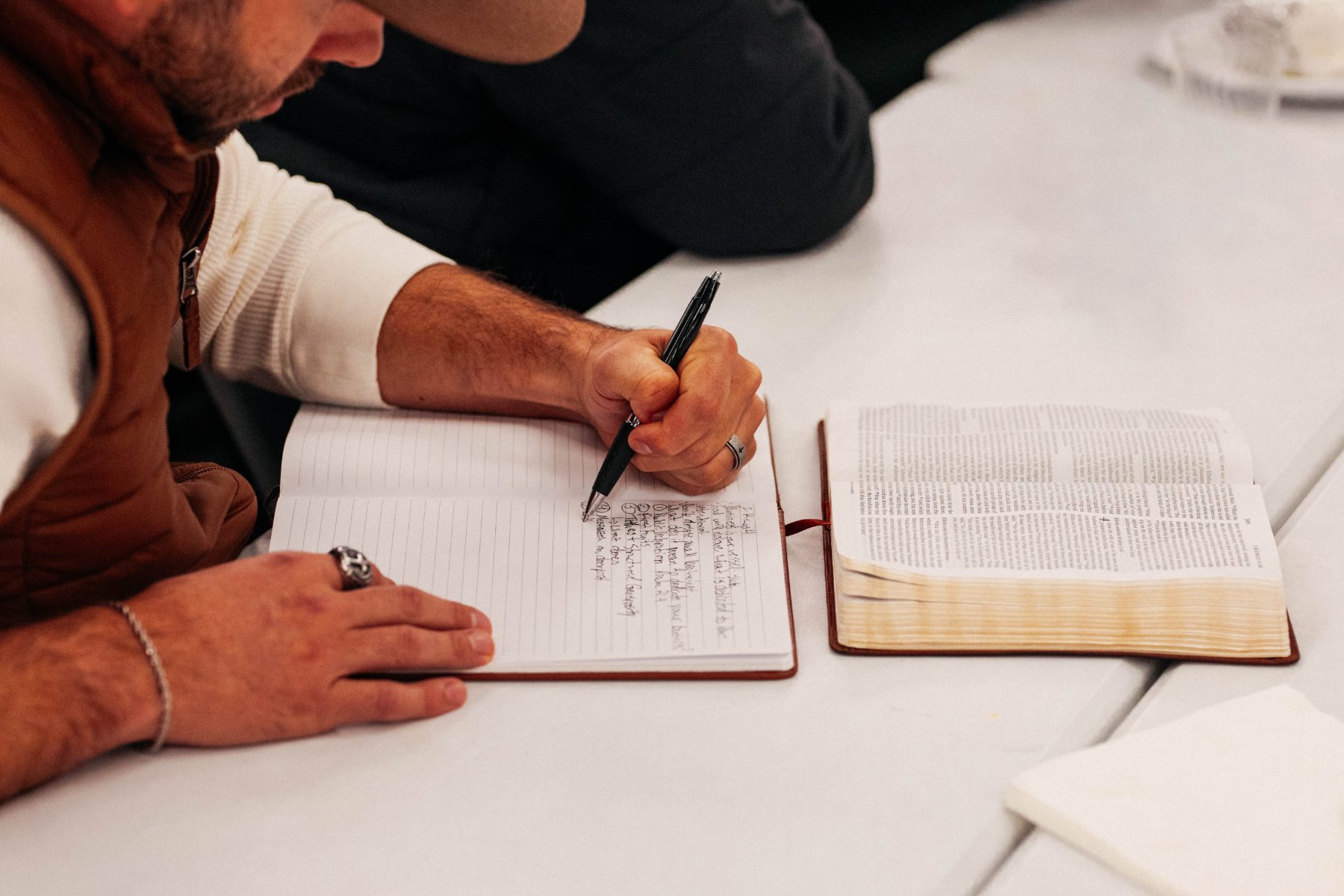 Writing out a plan beside an open Bible