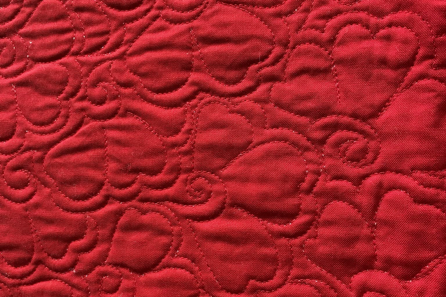 nærbilde av quilting - rød tråd på rød bakgrunn