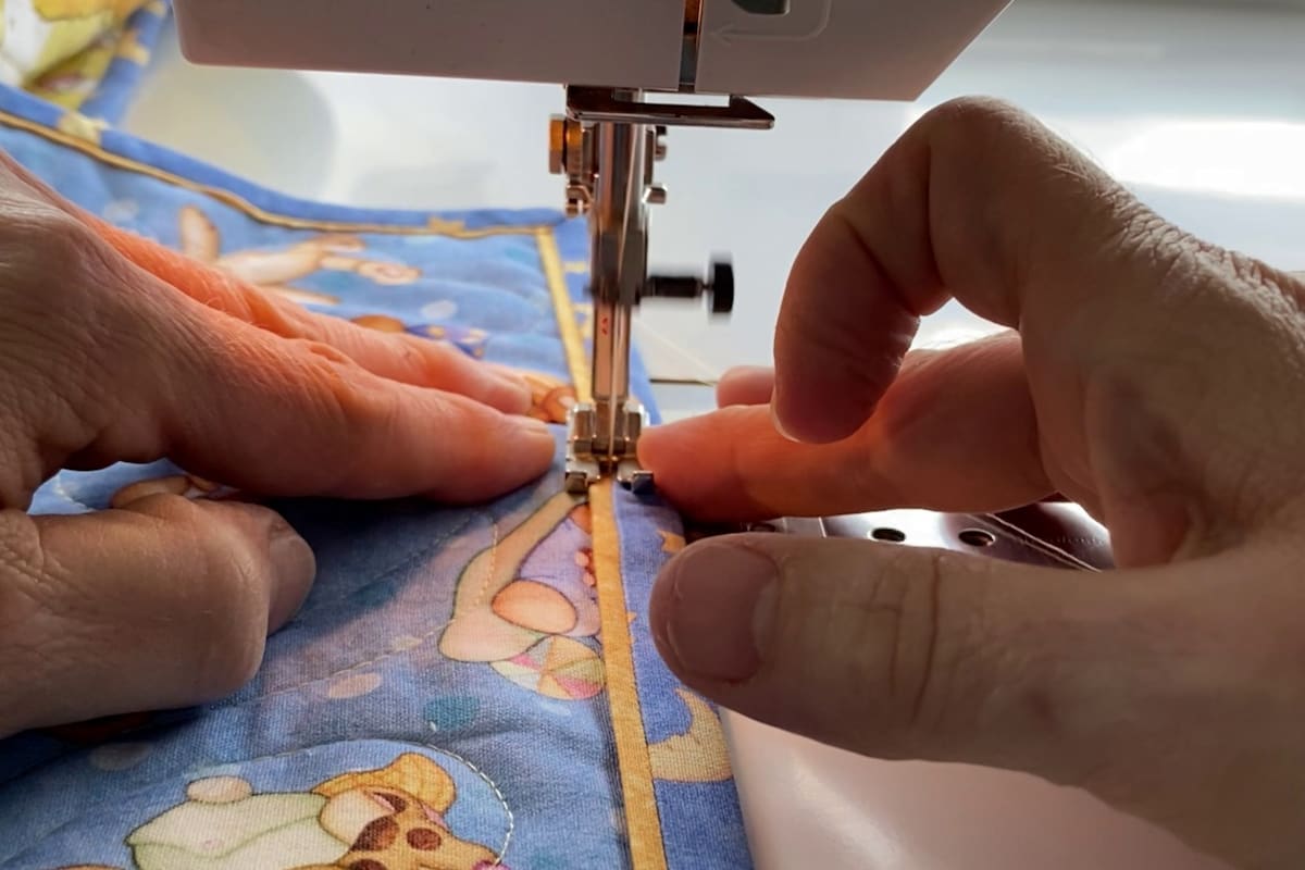 Nærbilde av en lukkekant som sys på en quilt med symaskin.