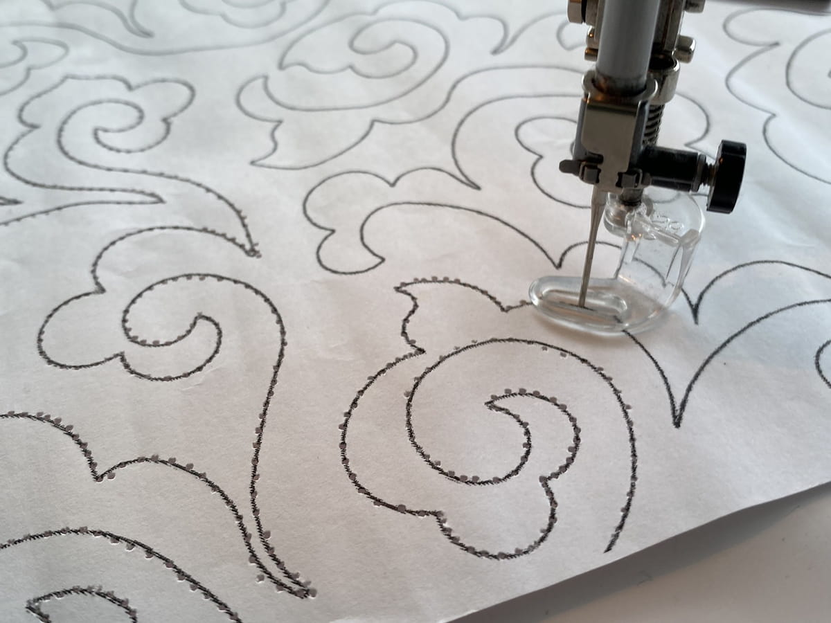 Nærbilde av et papirmønster for quilting under en symaskin Nærbilde av et papirmønster for quilting under en symaskin