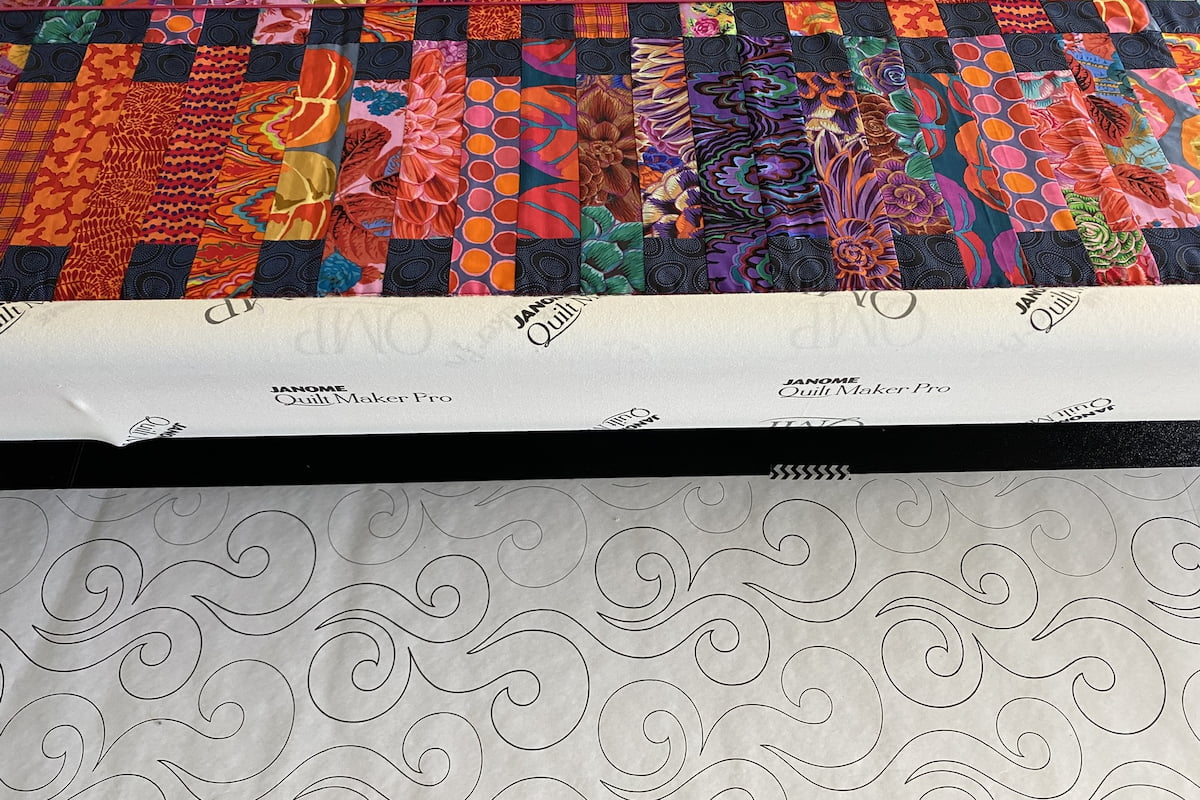 Quilt i rødtoner satt opp på en longarm. Du ser quilten og den pantografen som skal quiltes Quilt i rødtoner satt opp på en longarm. Du ser quilten og den pantografen som skal quiltes