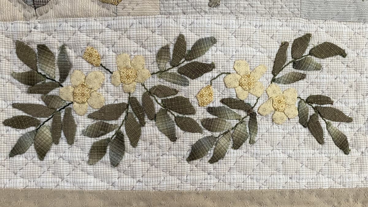 Nærbilde av applikert quiltblokk i duse farger, gule blomster på lys grå bakgrunn, japanske stoffer, håndquiltet Nærbilde av applikert quiltblokk i duse farger, gule blomster på lys grå bakgrunn, japanske stoffer, håndquiltet