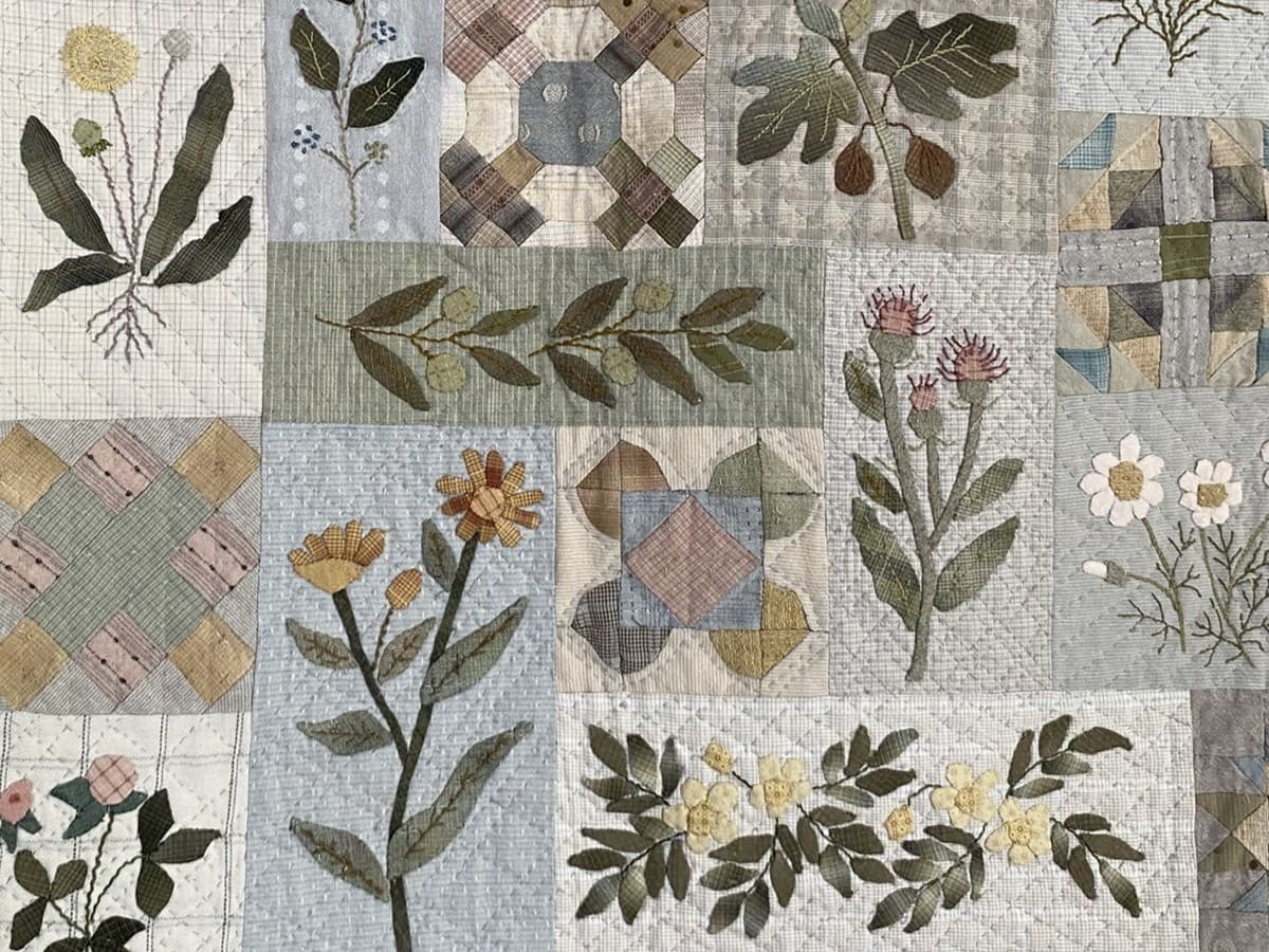 Nærbilde av noen blokker i en applikert quilt i duse farger. Bildet illustrerer hvordan håndquiltingen varierer mellom de ulike blokkene Nærbilde av noen blokker i en applikert quilt i duse farger. Bildet illustrerer hvordan håndquiltingen varierer mellom de ulike blokkene