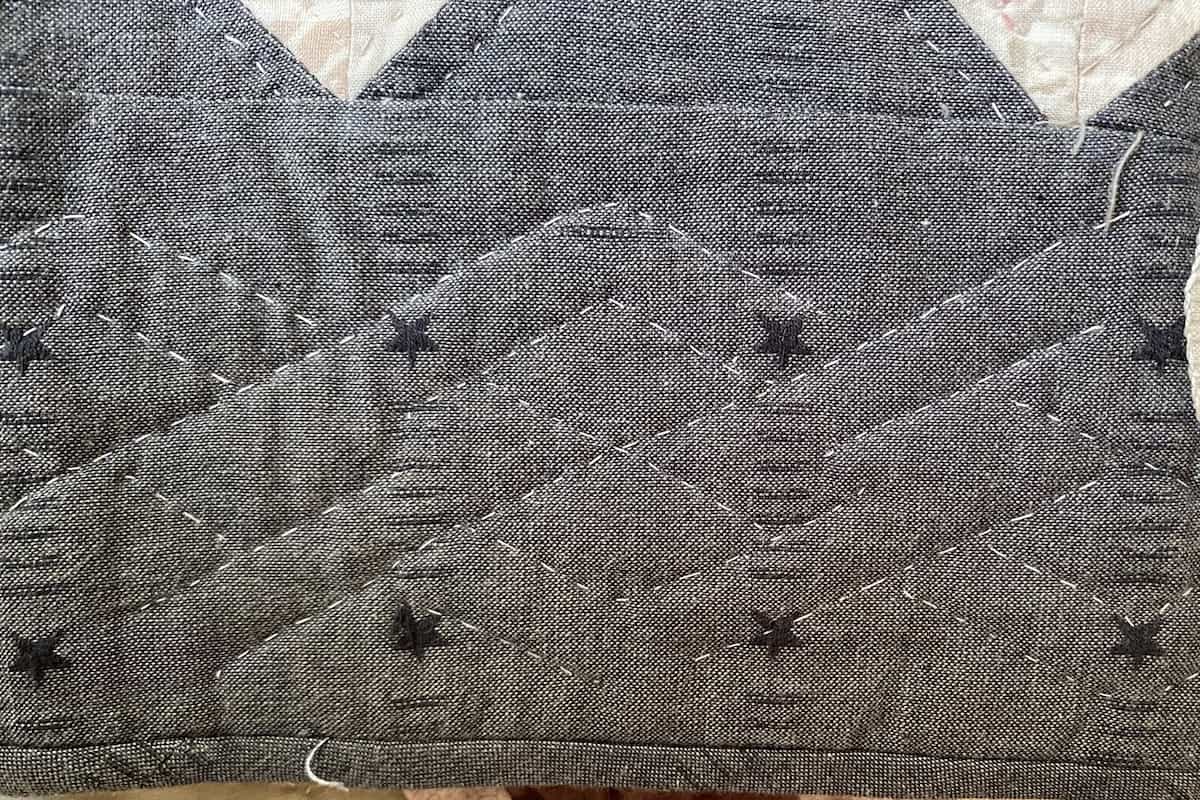 Nærbilde av en bord på en quilt, håndquiltet med en kabelbord med rette linjer Nærbilde av en bord på en quilt, håndquiltet med en kabelbord med rette linjer