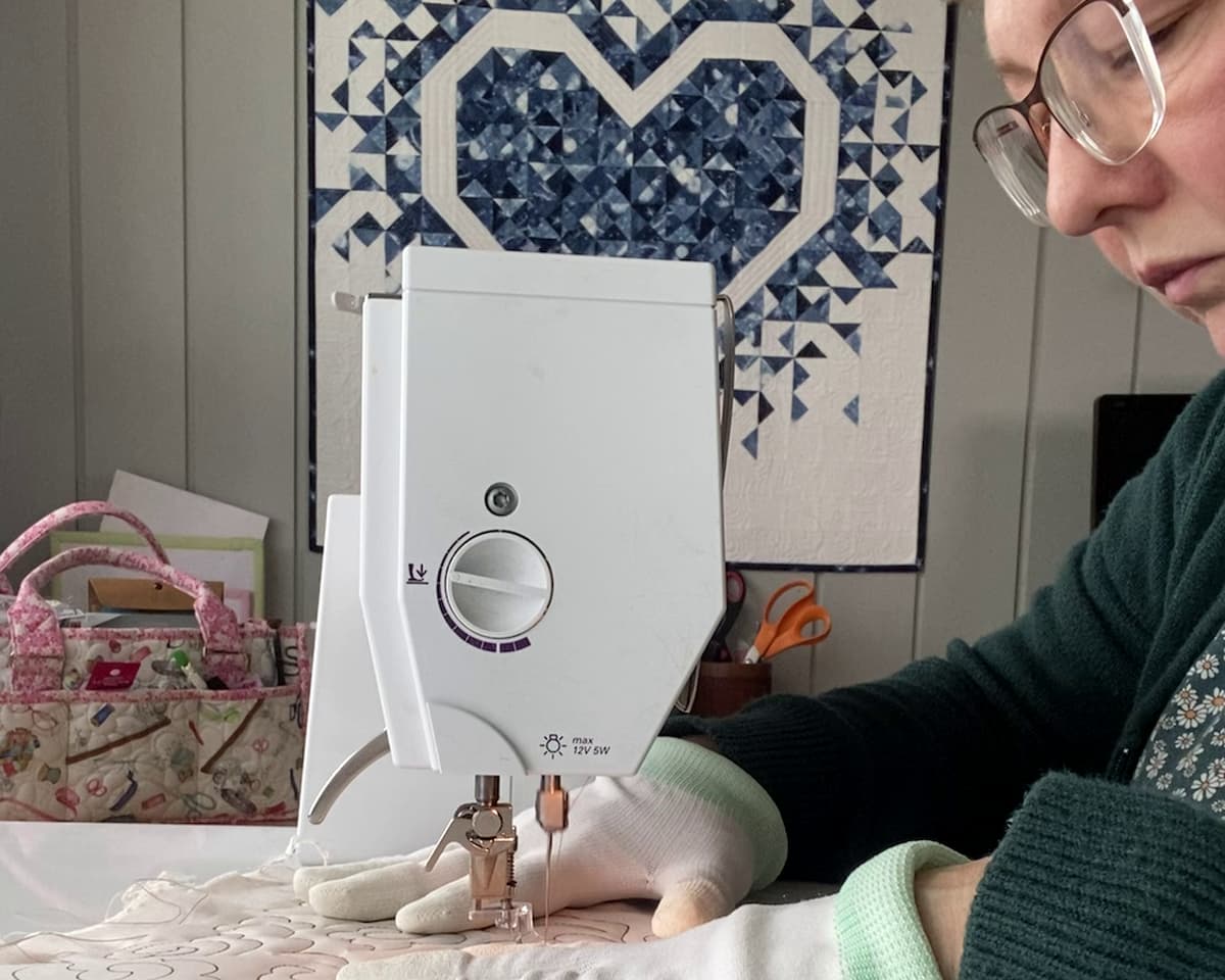 nærbilde av person som sitter ved symaskinen og quilter nærbilde av person som sitter ved symaskinen og quilter