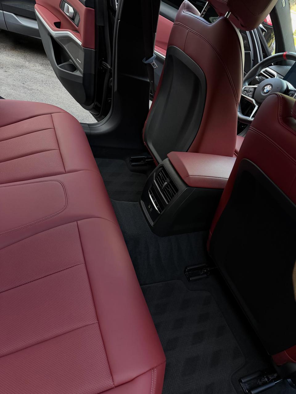 Red leather rear seats and black carpet in a BMW, cleaned and conditioned
