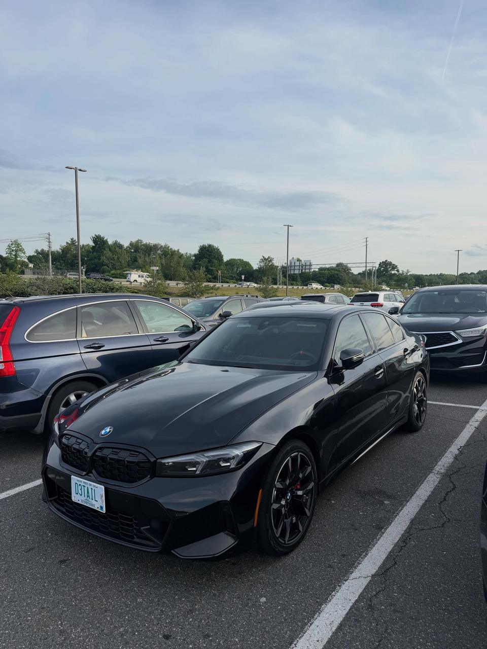 A black BMW M340i parked in a lot, reflecting the sky