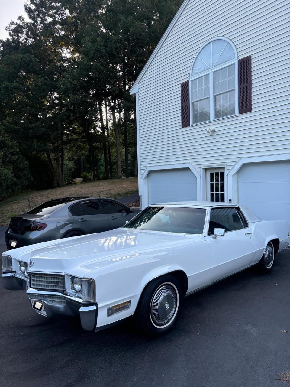 A white classic Cadillac Eldorado, freshly washed in a driveway