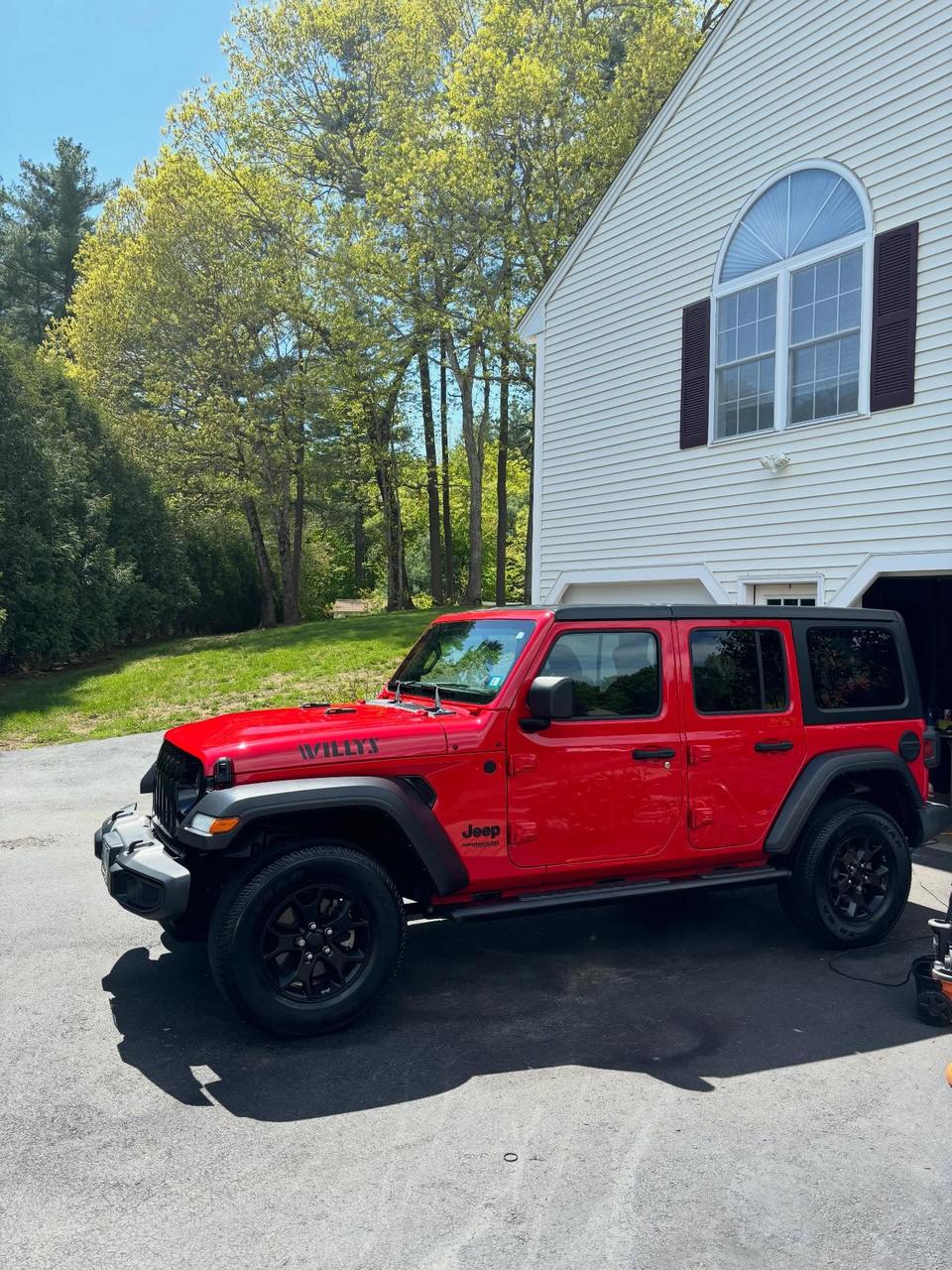 Side profile of a red Jeep Wrangler Willys after a hand wash