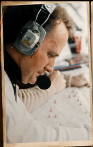 Charlie Mac calling a game in the broadcast booth, headset on