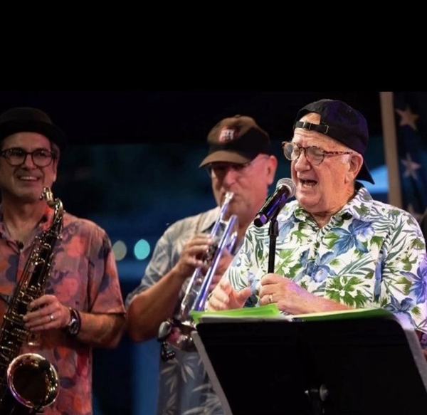 Charlie Mac singing on stage with the horn section
