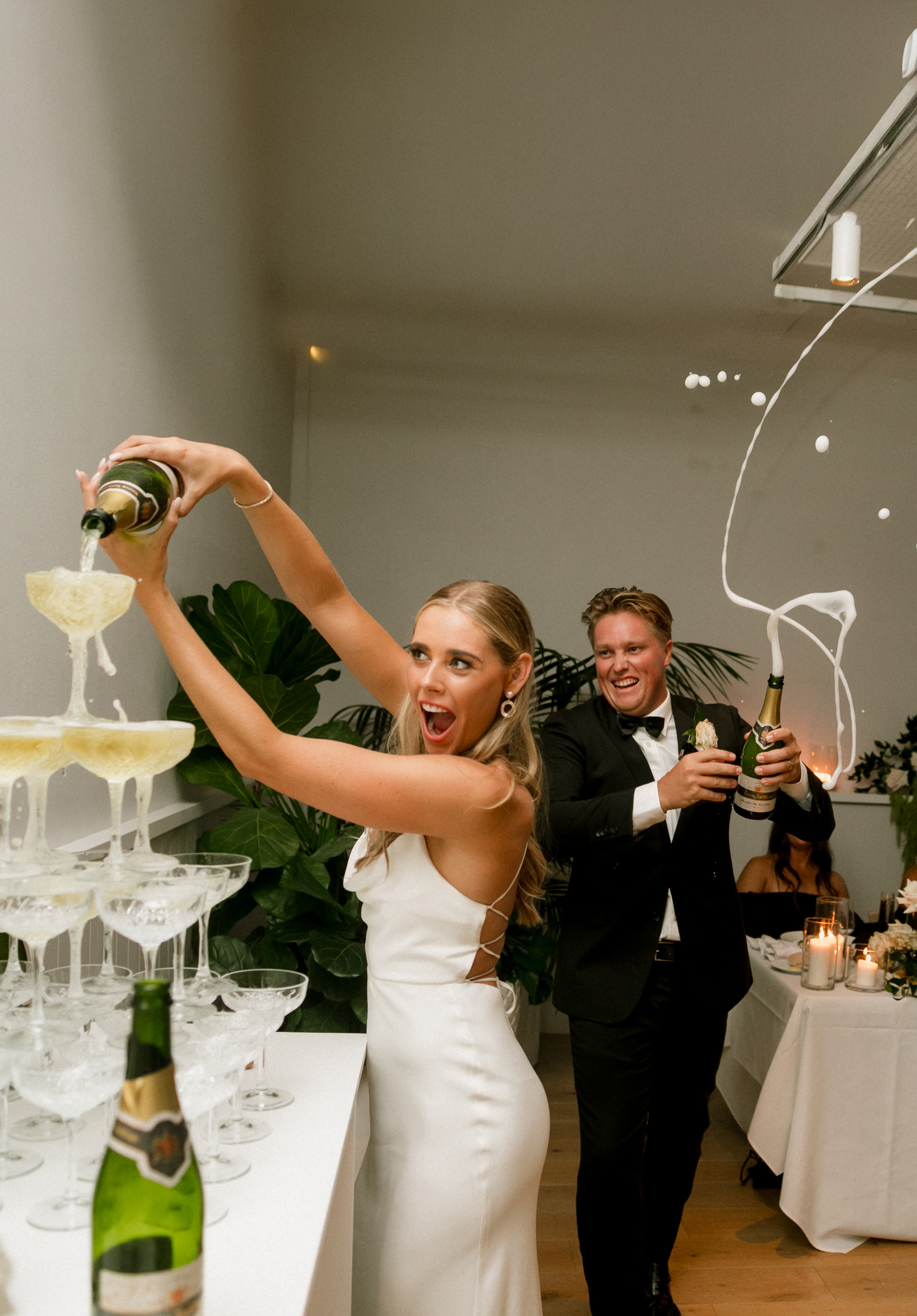 Bride drinking straight from the bottle in a white tux