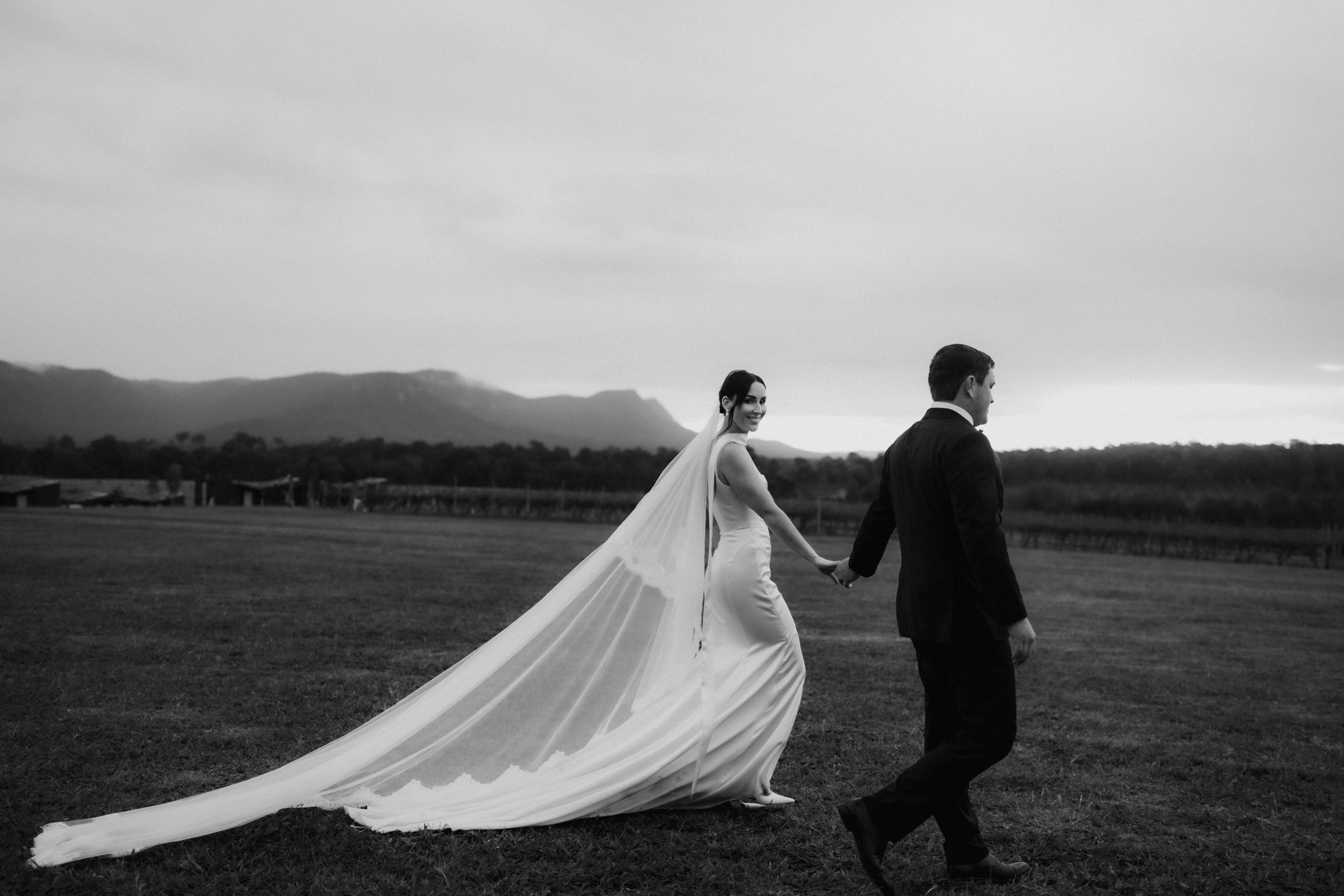 Long veil trailing across a field, black and white