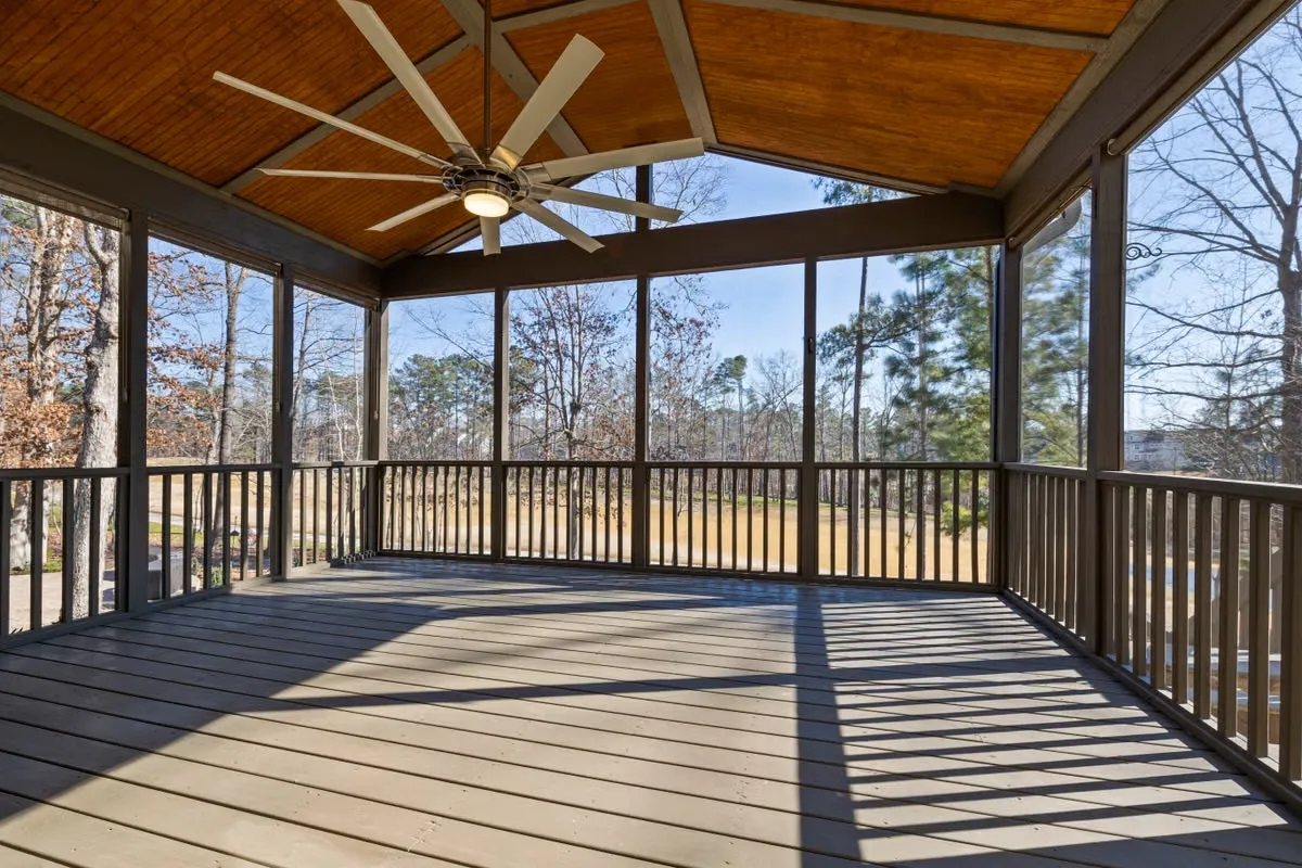 Screened porch with a ceiling fan and wood plank ceiling overlooking an open grassy yard