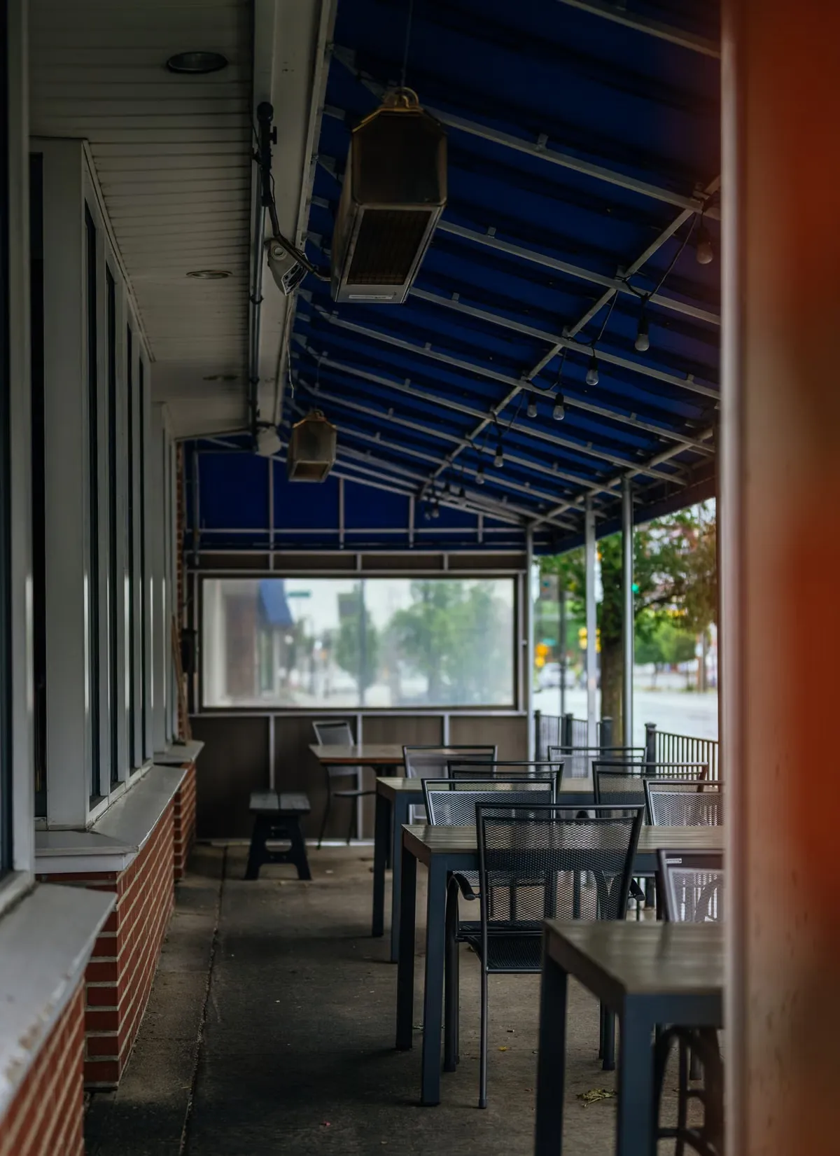Covered outdoor dining patio under a blue awning at a small local business