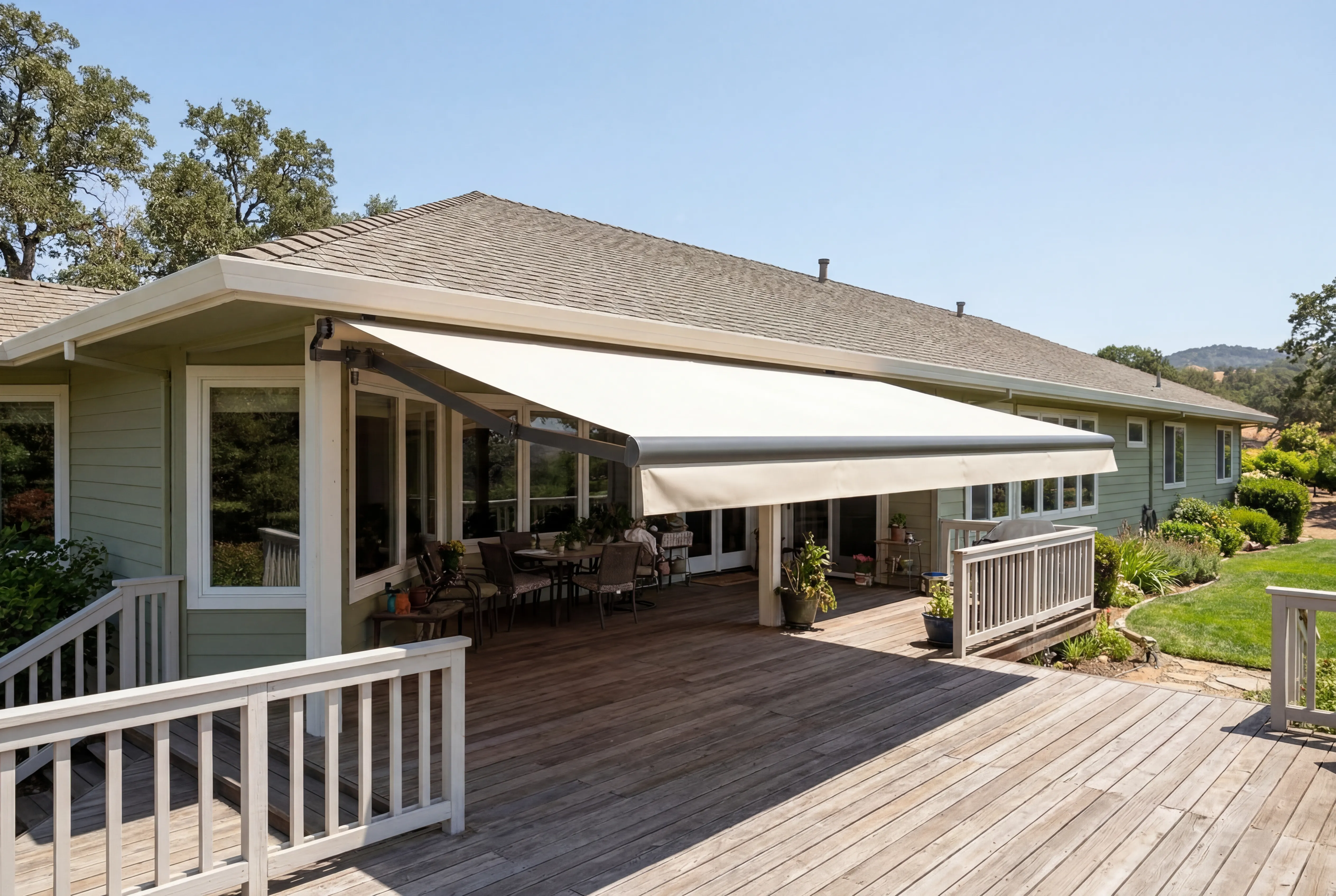 Ranch home with an awning extended over a wood deck, rolling hills visible in the distance