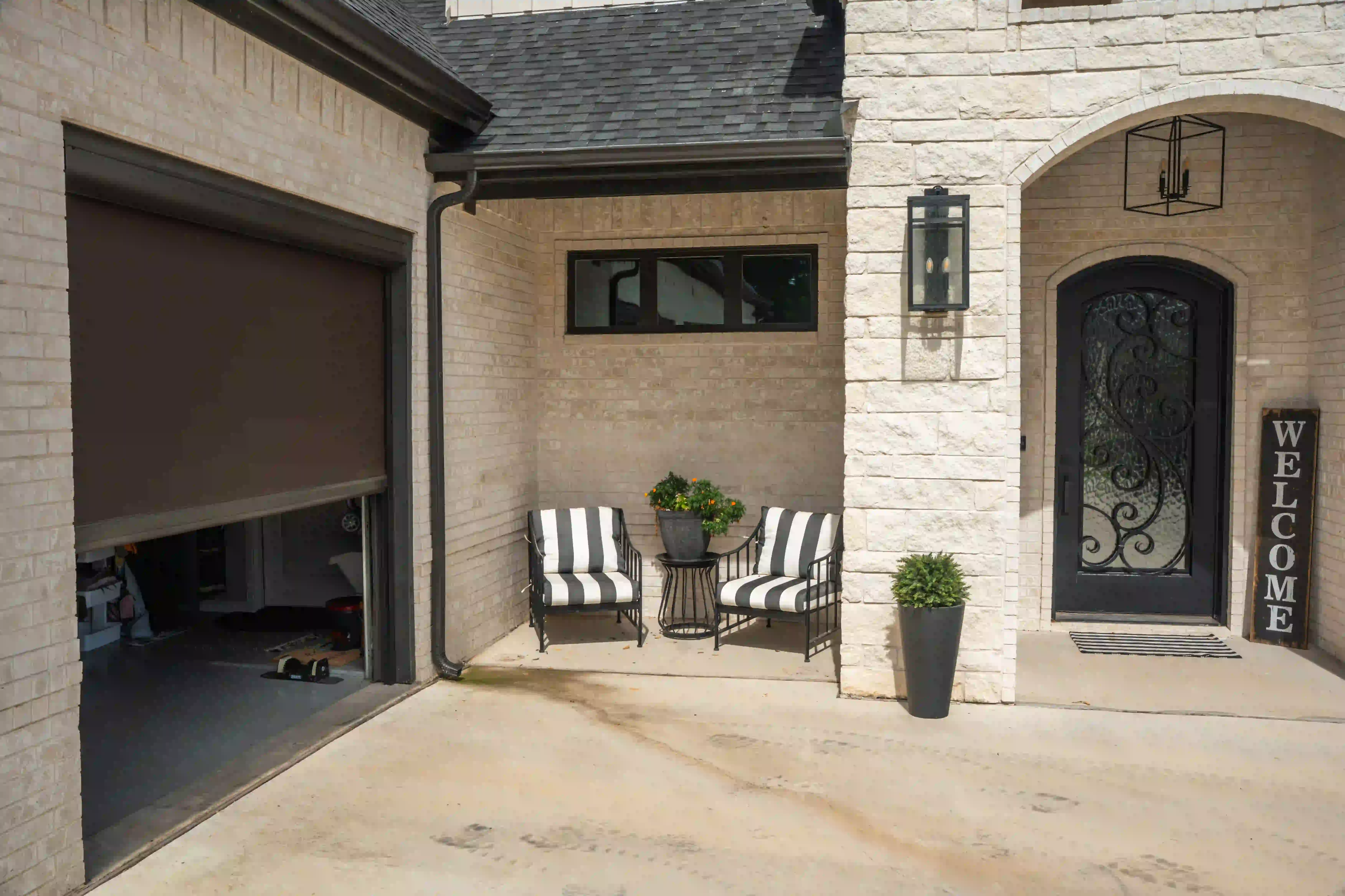 Stone courtyard entrance with a custom iron door and a garage solar screen extended on the left