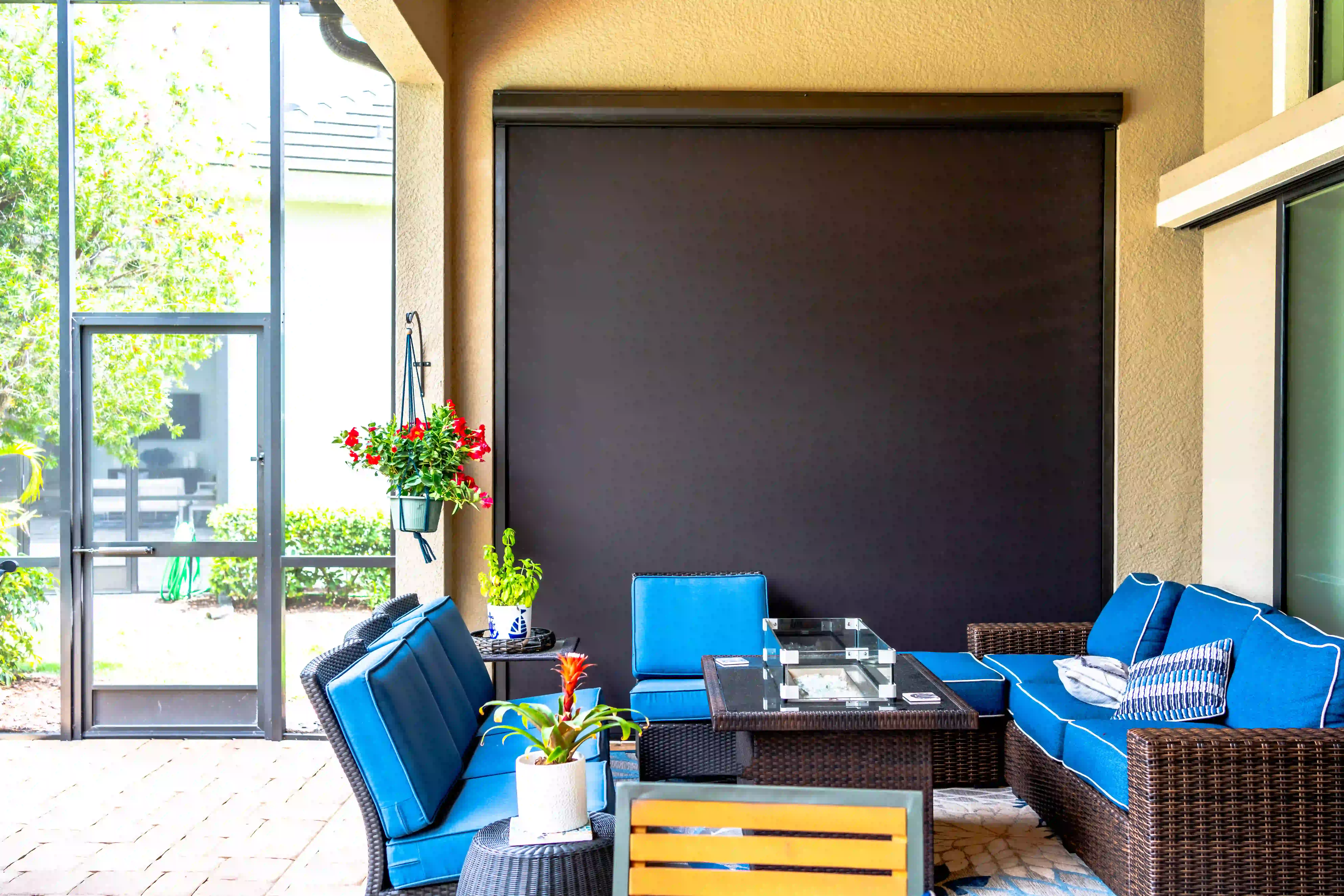 Large solar screen extended over a furnished patio seating area with a fire pit table