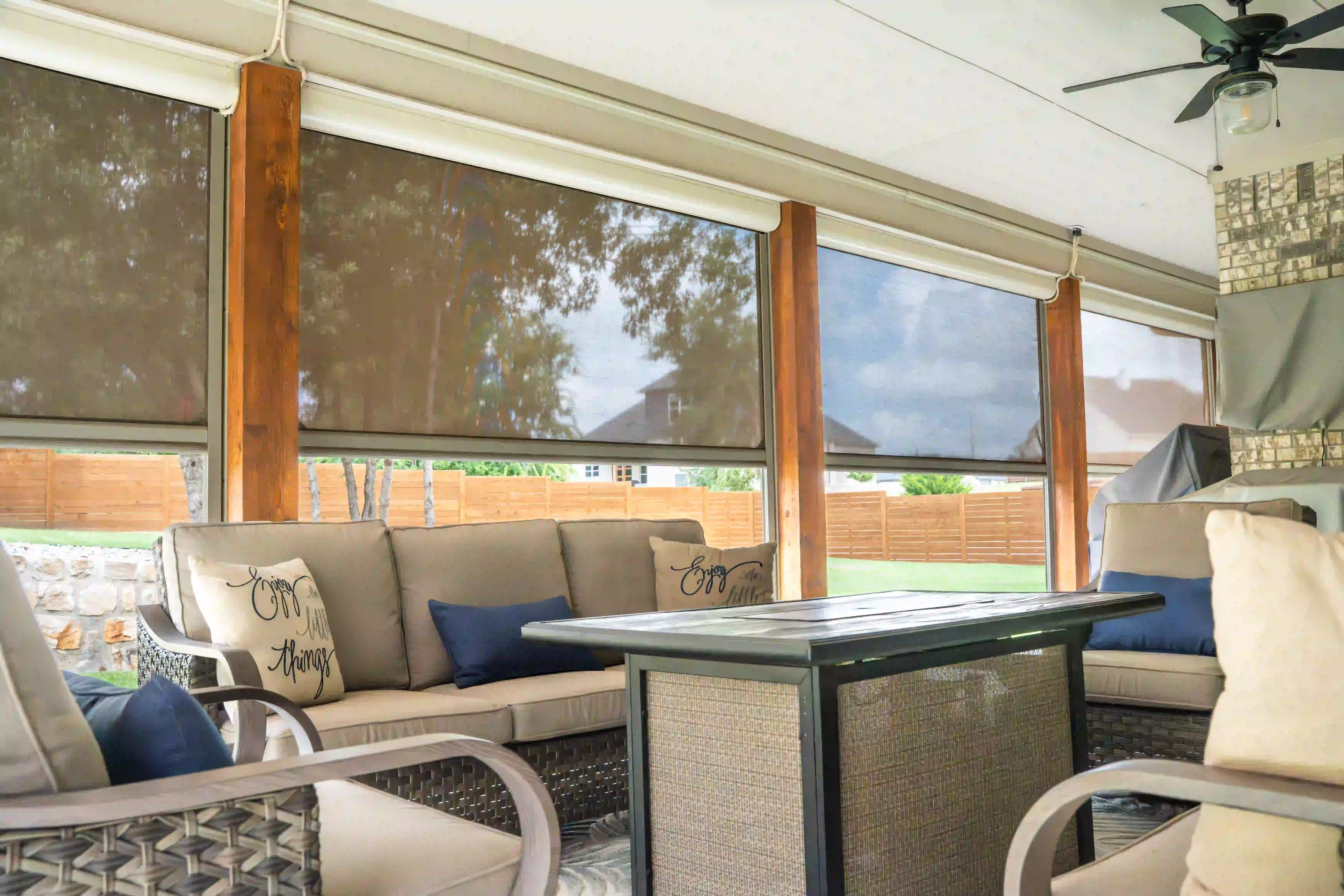 Covered patio interior with string-light-lined privacy screens and neighboring rooflines beyond