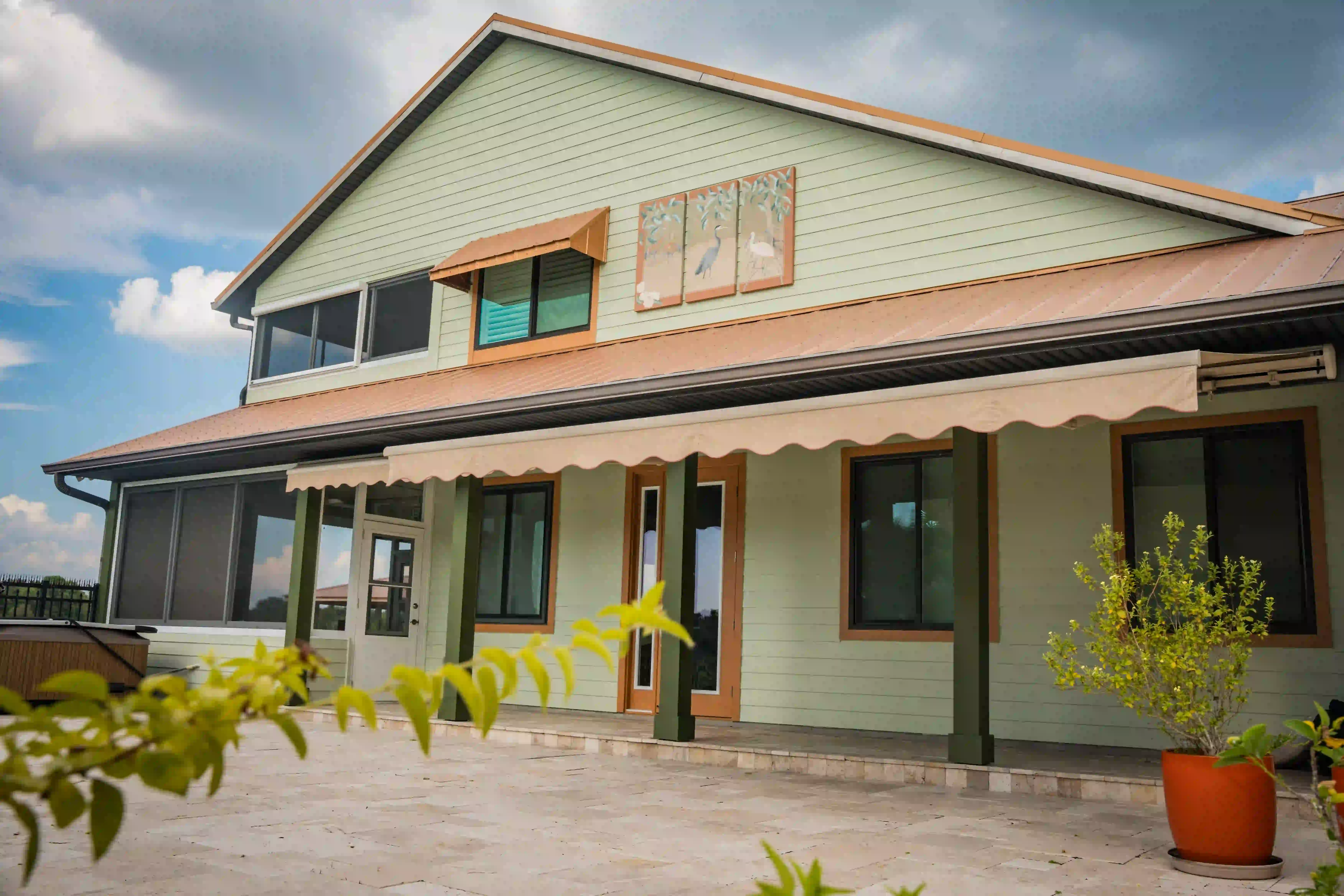 Two-story waterfront home with a real awning extended over its wraparound porch