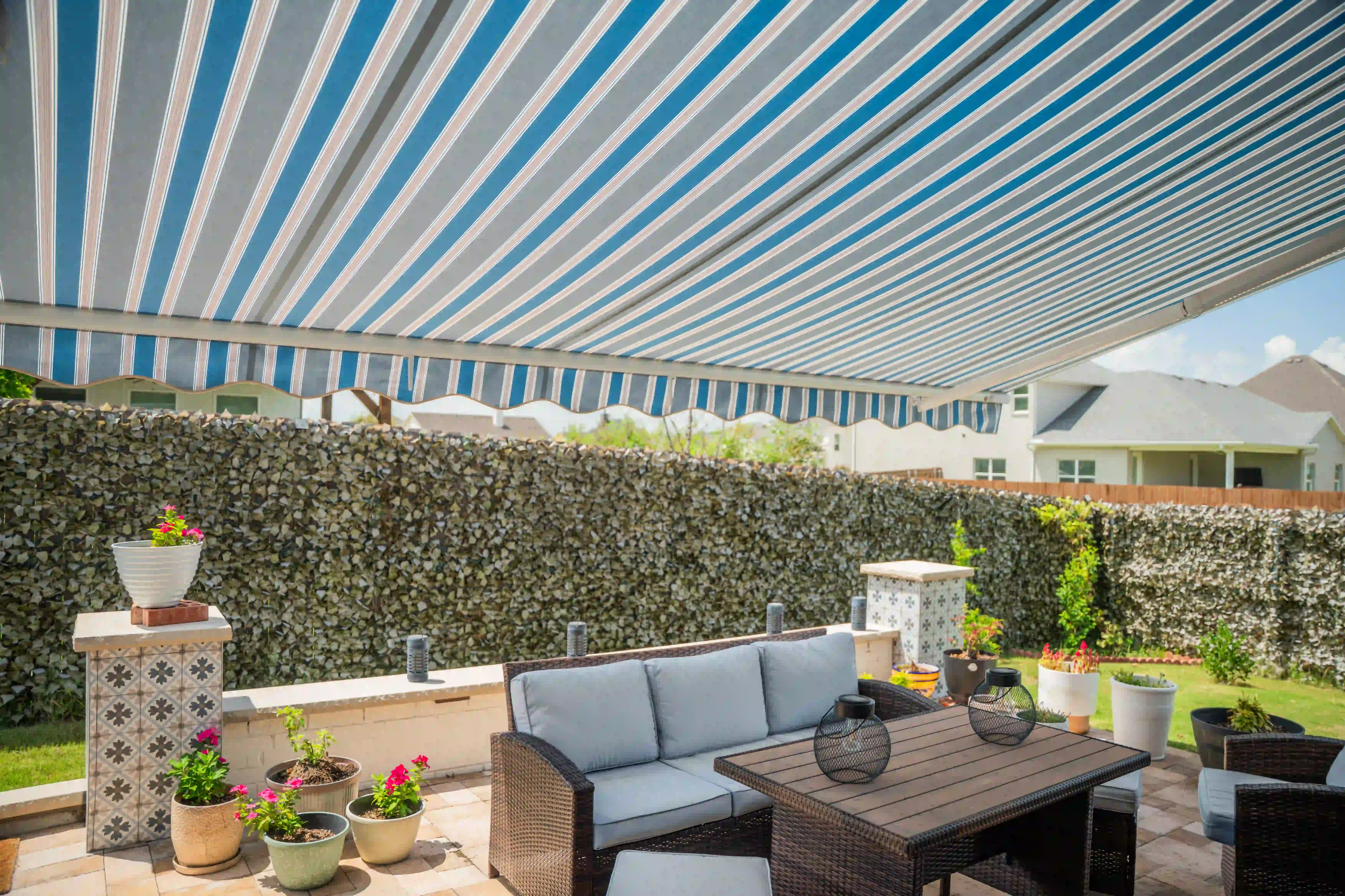 Striped awning over a suburban patio with a wicker sectional and neighboring subdivision houses