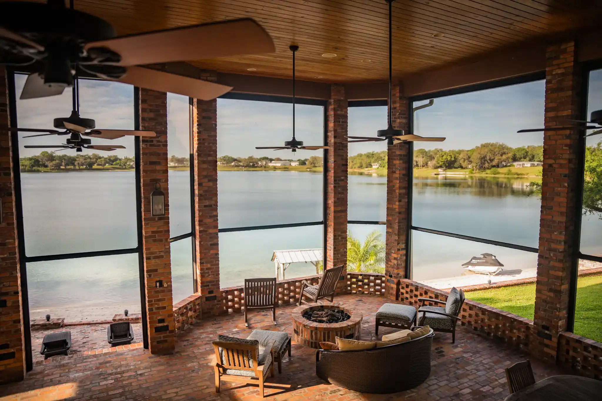 Screened brick porch overlooking open water and a sandy shoreline