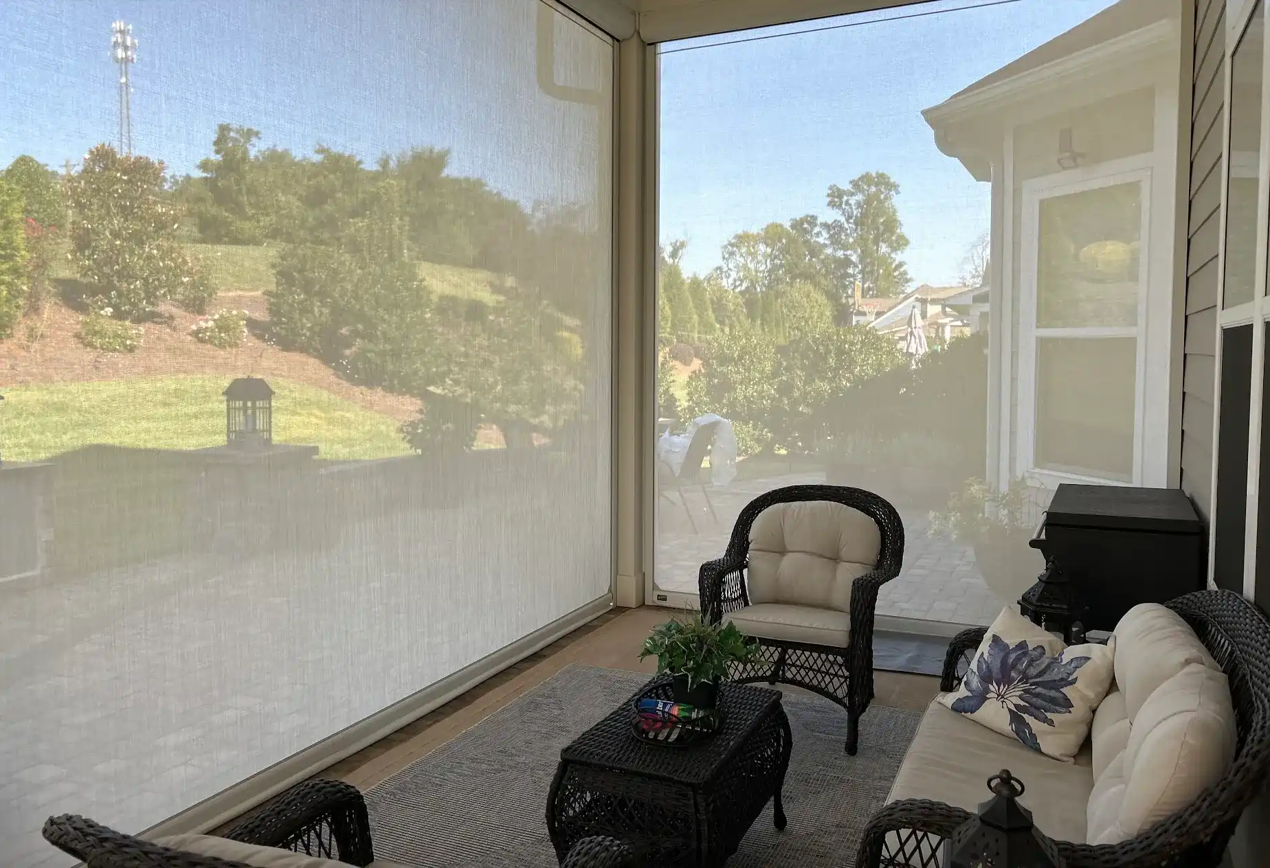 Screened porch interior with wicker seating overlooking a landscaped backyard