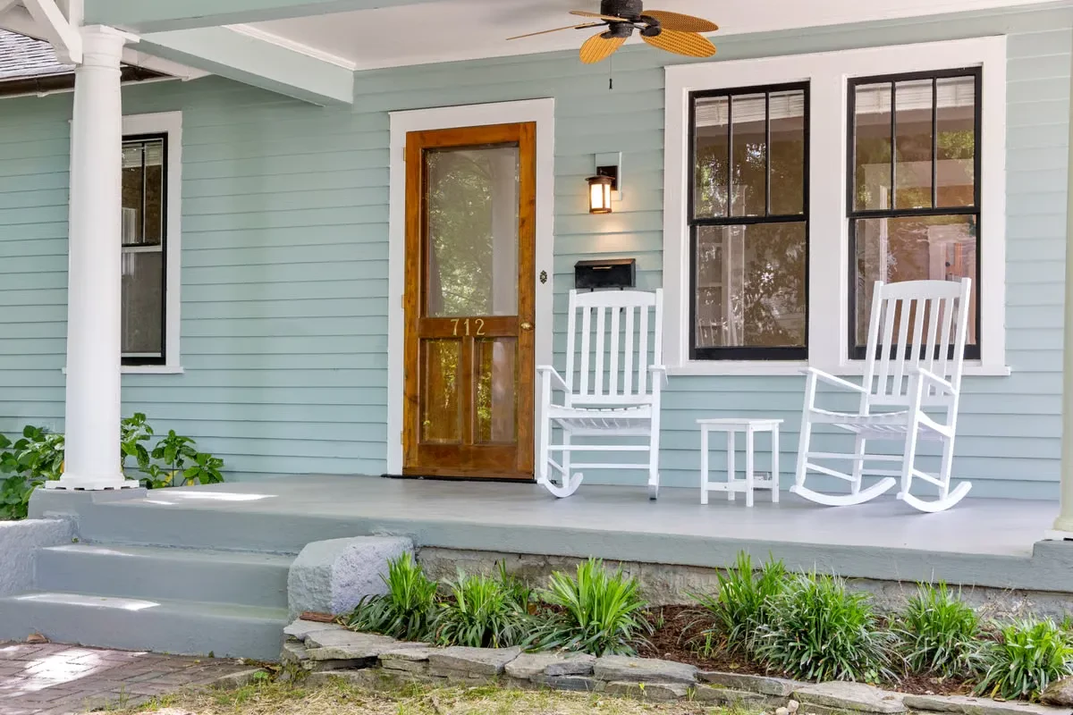 Craftsman-style covered front porch with white rocking chairs and a ceiling fan