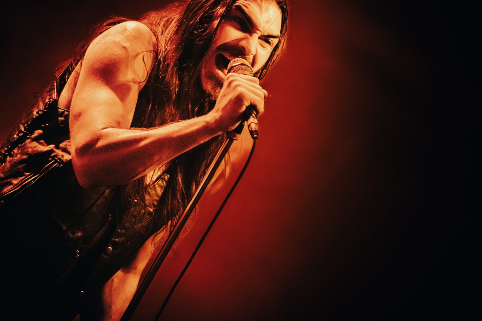 Brandon Yeagley performing live, head tilted into the microphone under deep red stage light.