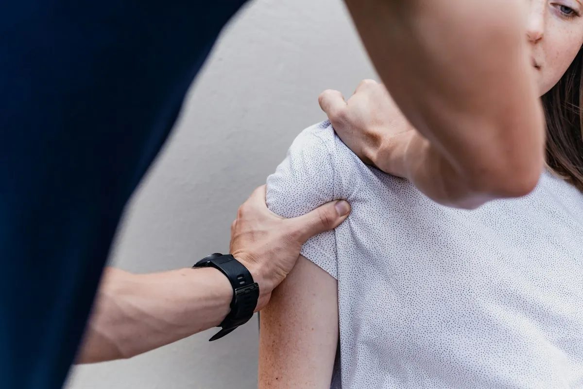 A therapist’s hands on a person’s shoulder
