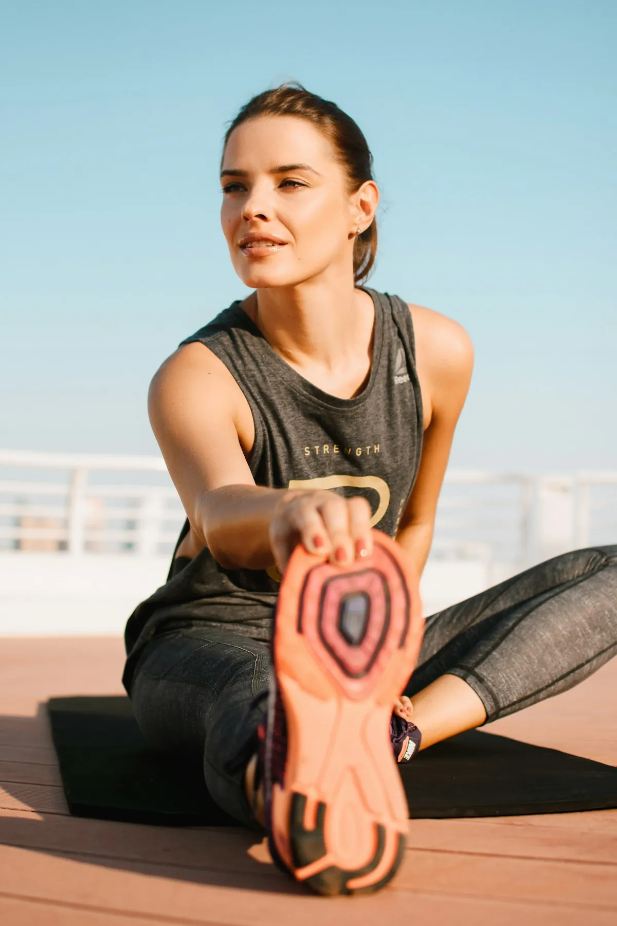 A woman stretching on a mat outdoors
